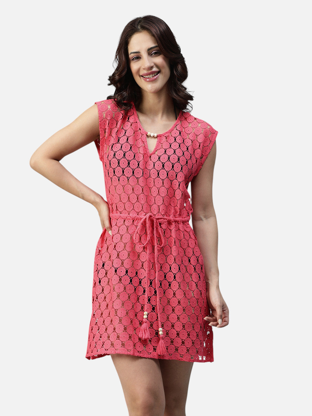 Woman wearing a pink crochet short dress with tassel belt and cap sleeves