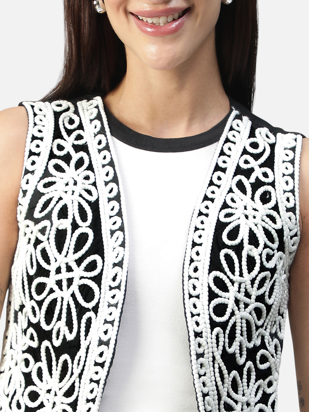 Woman wearing a sleeveless top with white floral embroidery on black panels