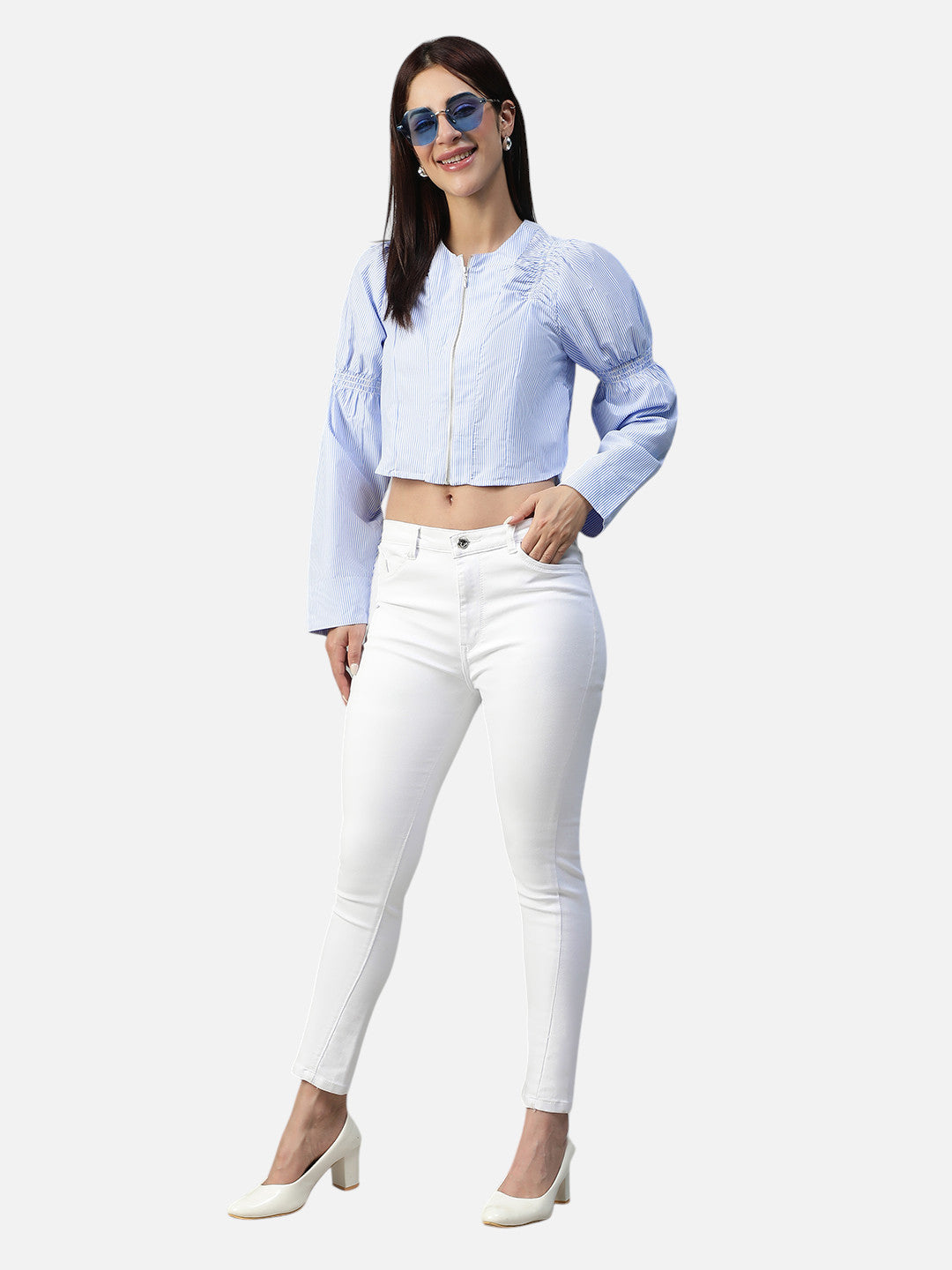 Woman in a light blue crop top with balloon sleeves, white skinny jeans, and heels