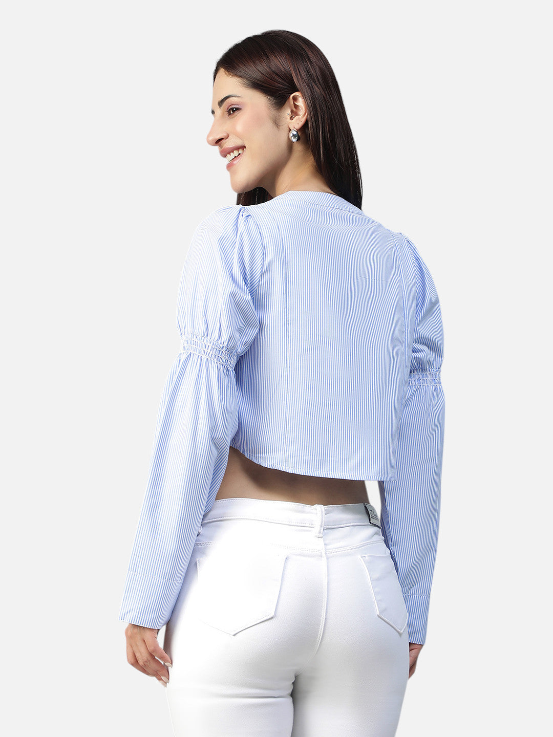 Woman in a blue striped long sleeve crop top and white jeans, back view.