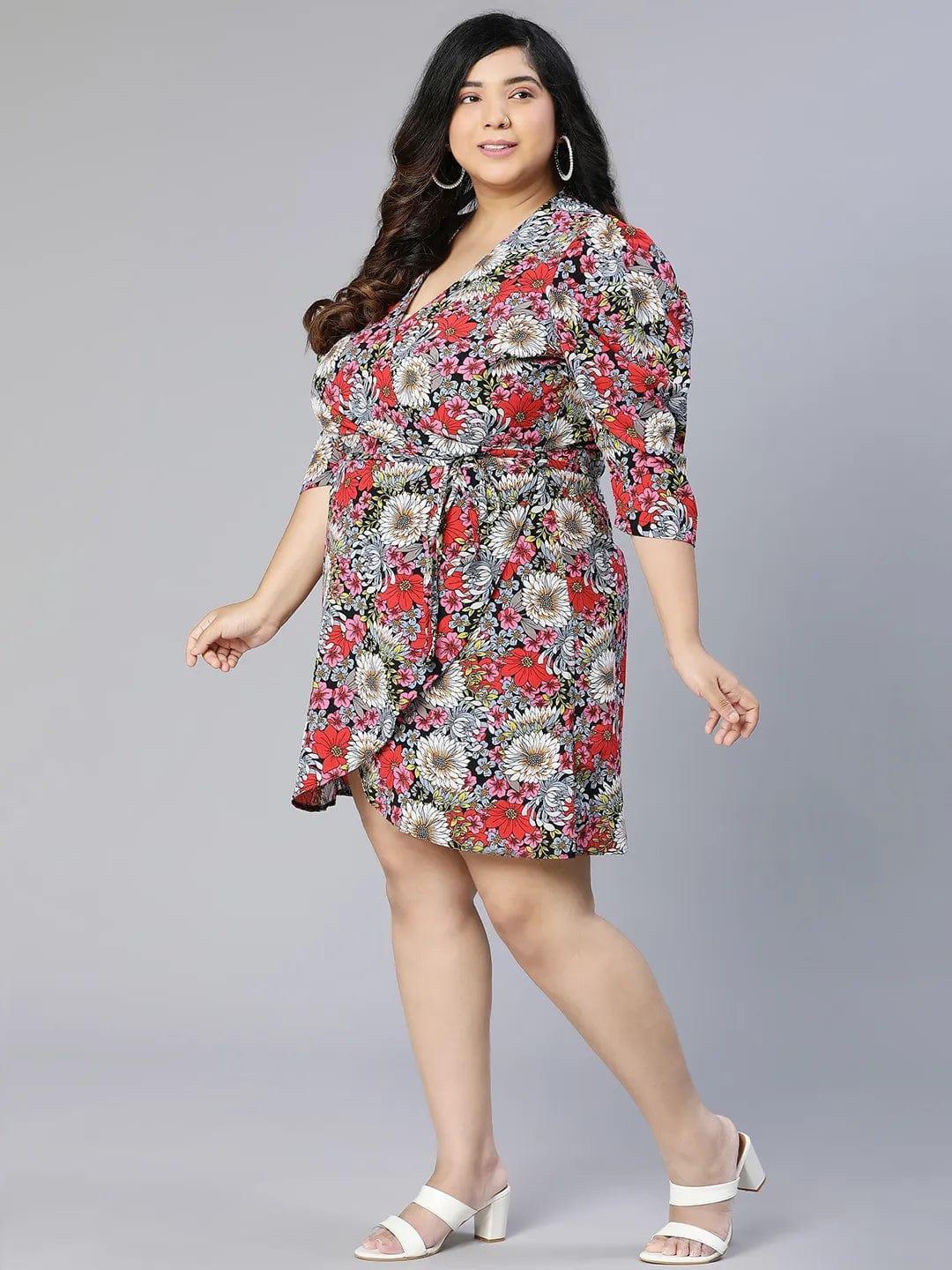 A woman wearing a floral print dress and white sandals is posing for a photograph.