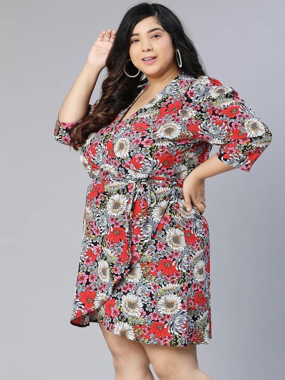 A woman wearing a floral print dress and white sandals is posing for a photograph.