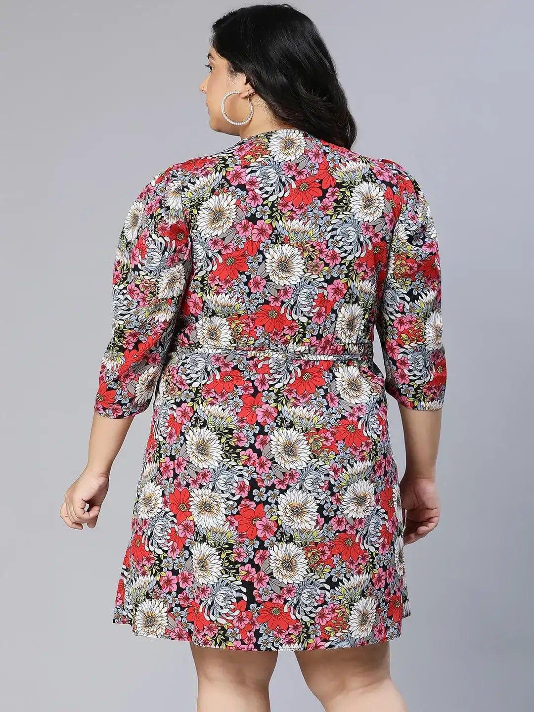 A woman wearing a floral print dress and white sandals is posing for a photograph.