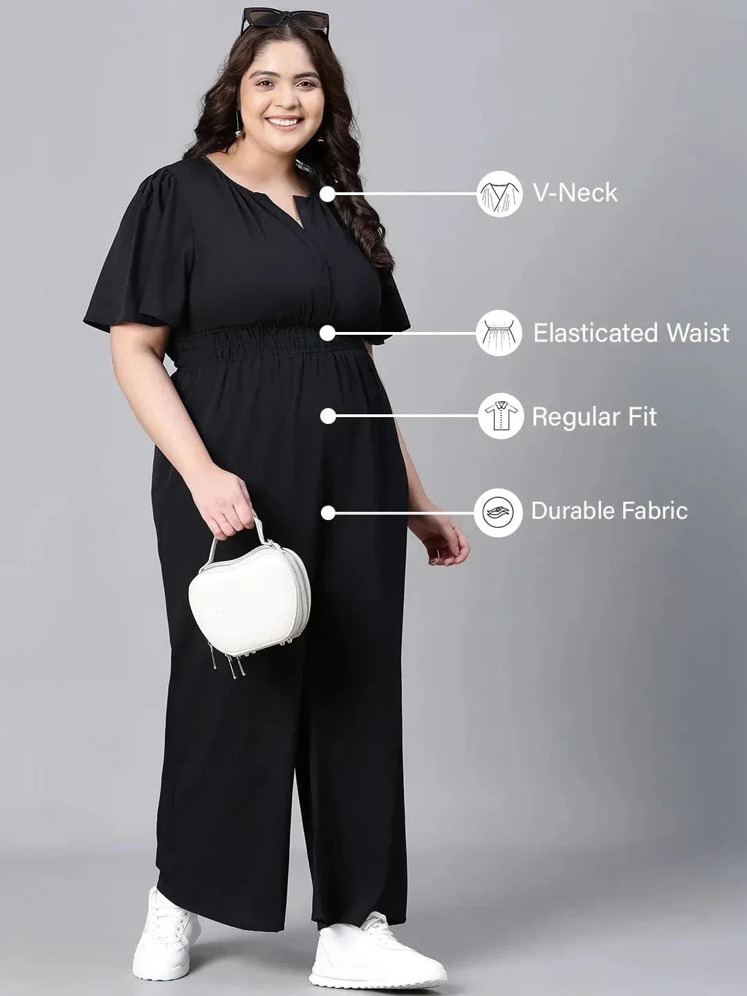 A woman wearing a black jumpsuit with a high neckline and short sleeves, smiling at the camera.