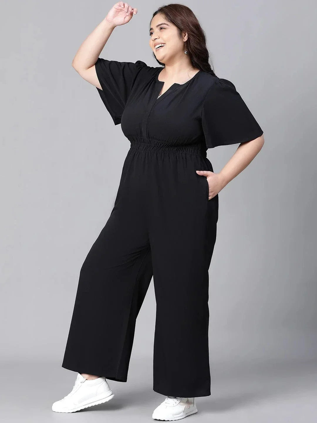 A woman wearing a black jumpsuit with a high neckline and short sleeves, smiling at the camera.