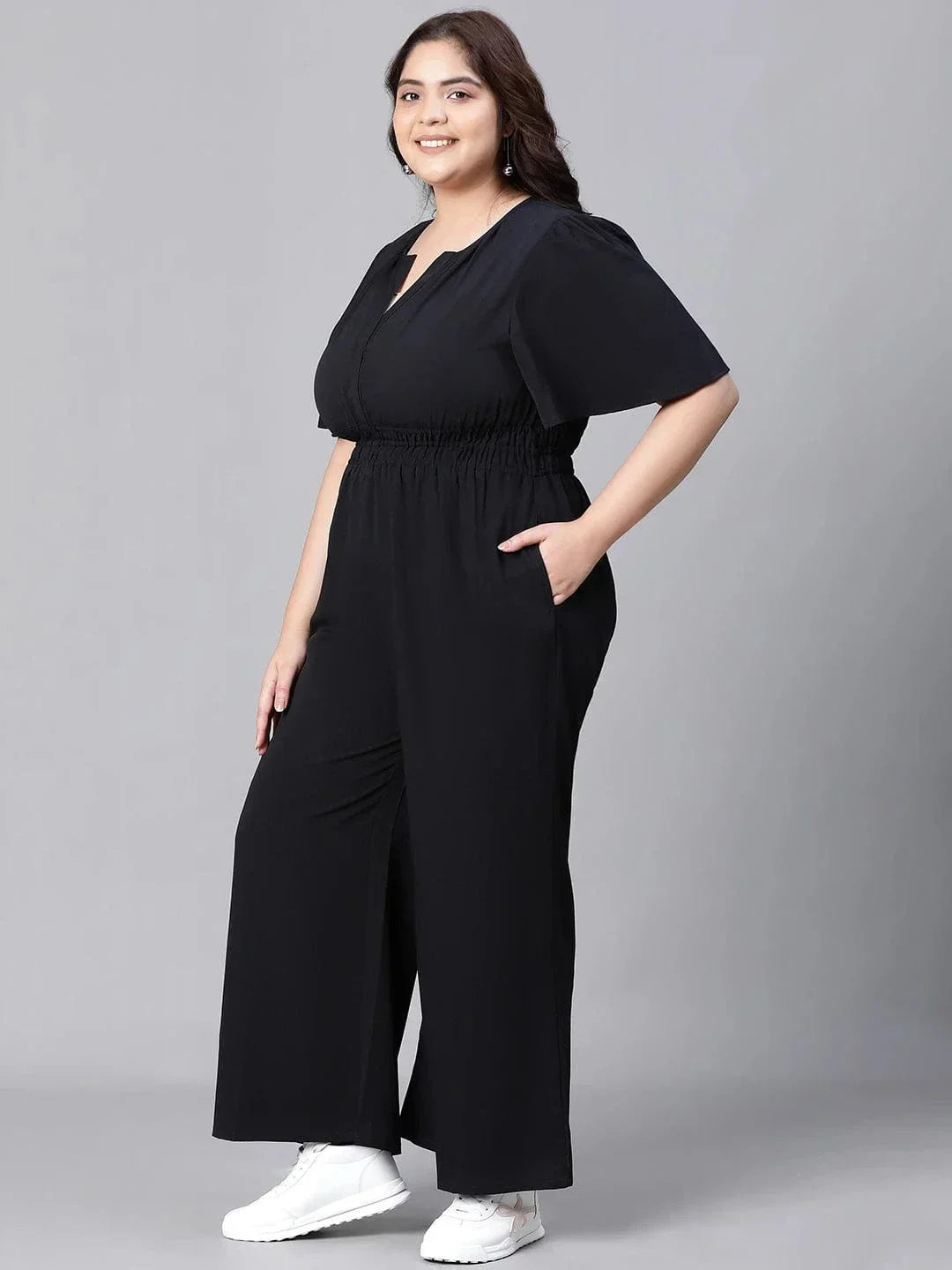 A woman wearing a black jumpsuit with a high neckline and short sleeves, smiling at the camera.