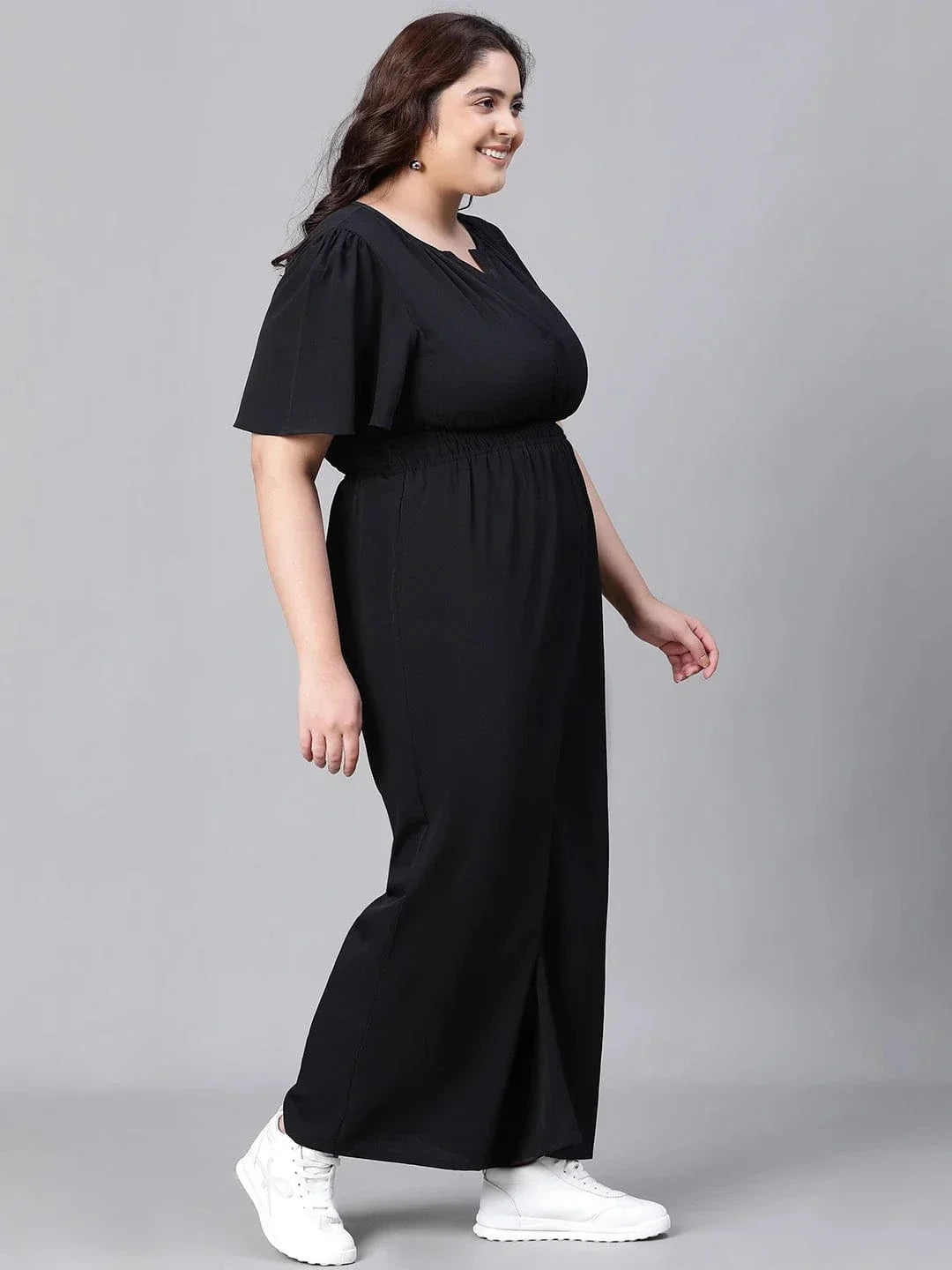 A woman wearing a black jumpsuit with a high neckline and short sleeves, smiling at the camera.