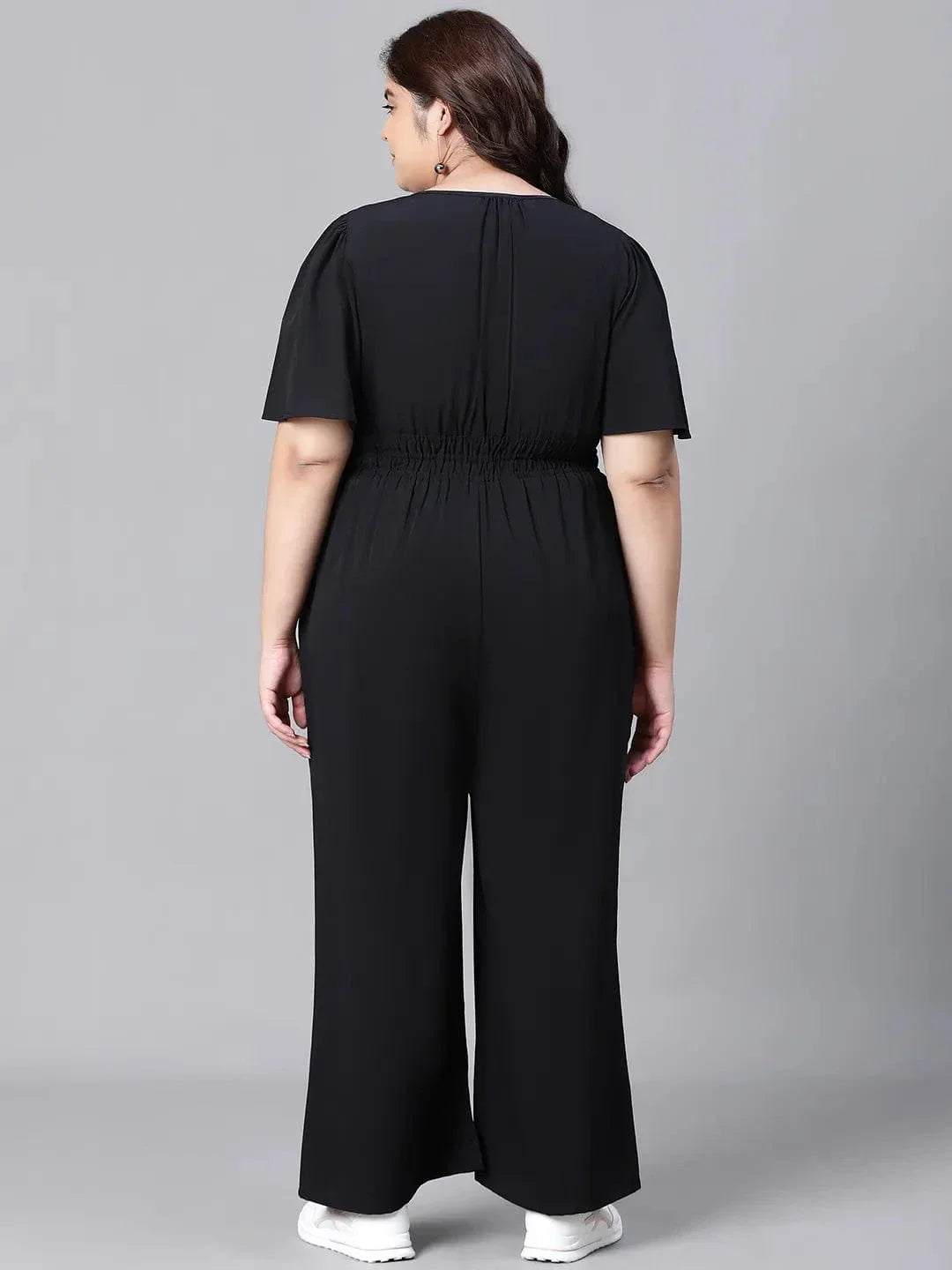 A woman wearing a black jumpsuit with a high neckline and short sleeves, smiling at the camera.