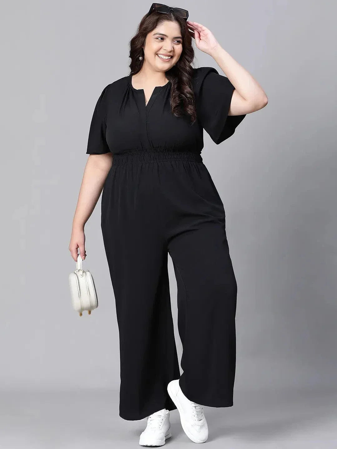 A woman wearing a black jumpsuit with a high neckline and short sleeves, smiling at the camera.