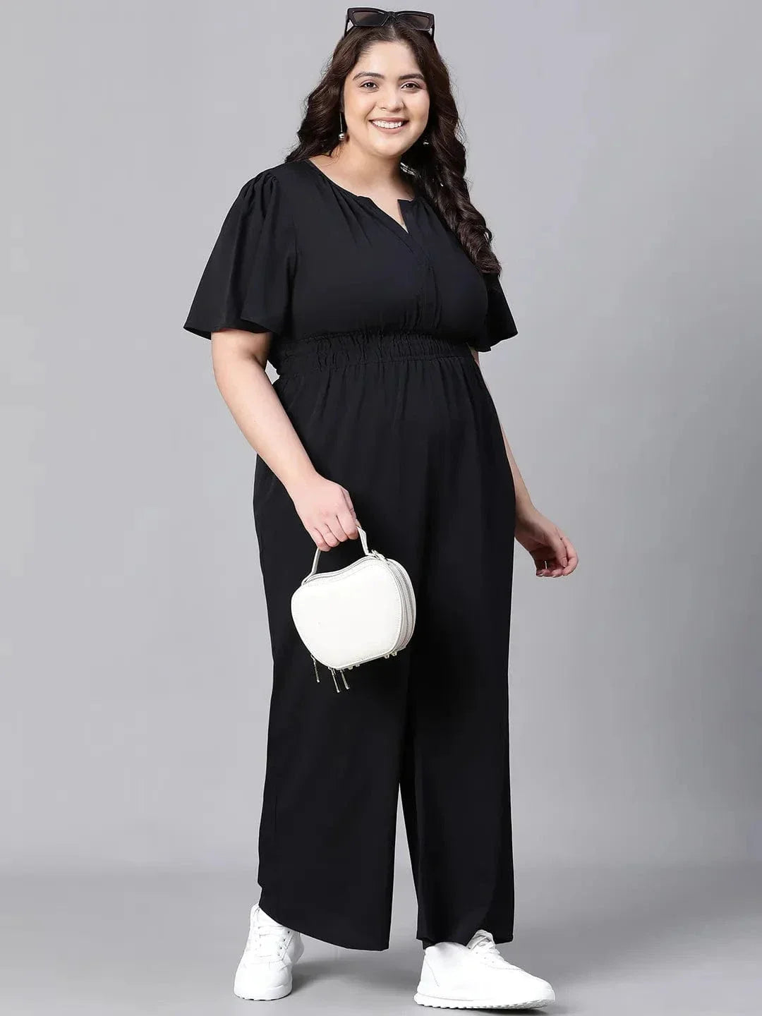 A woman wearing a black jumpsuit with a high neckline and short sleeves, smiling at the camera.