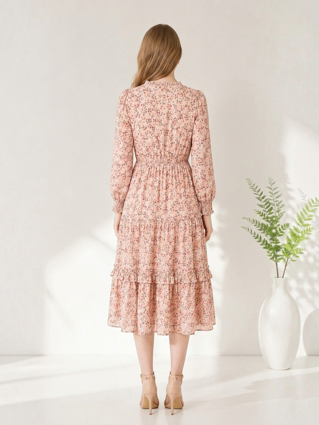 Pink floral midi dress with ruffled tiers and long sleeves, paired with beige heels