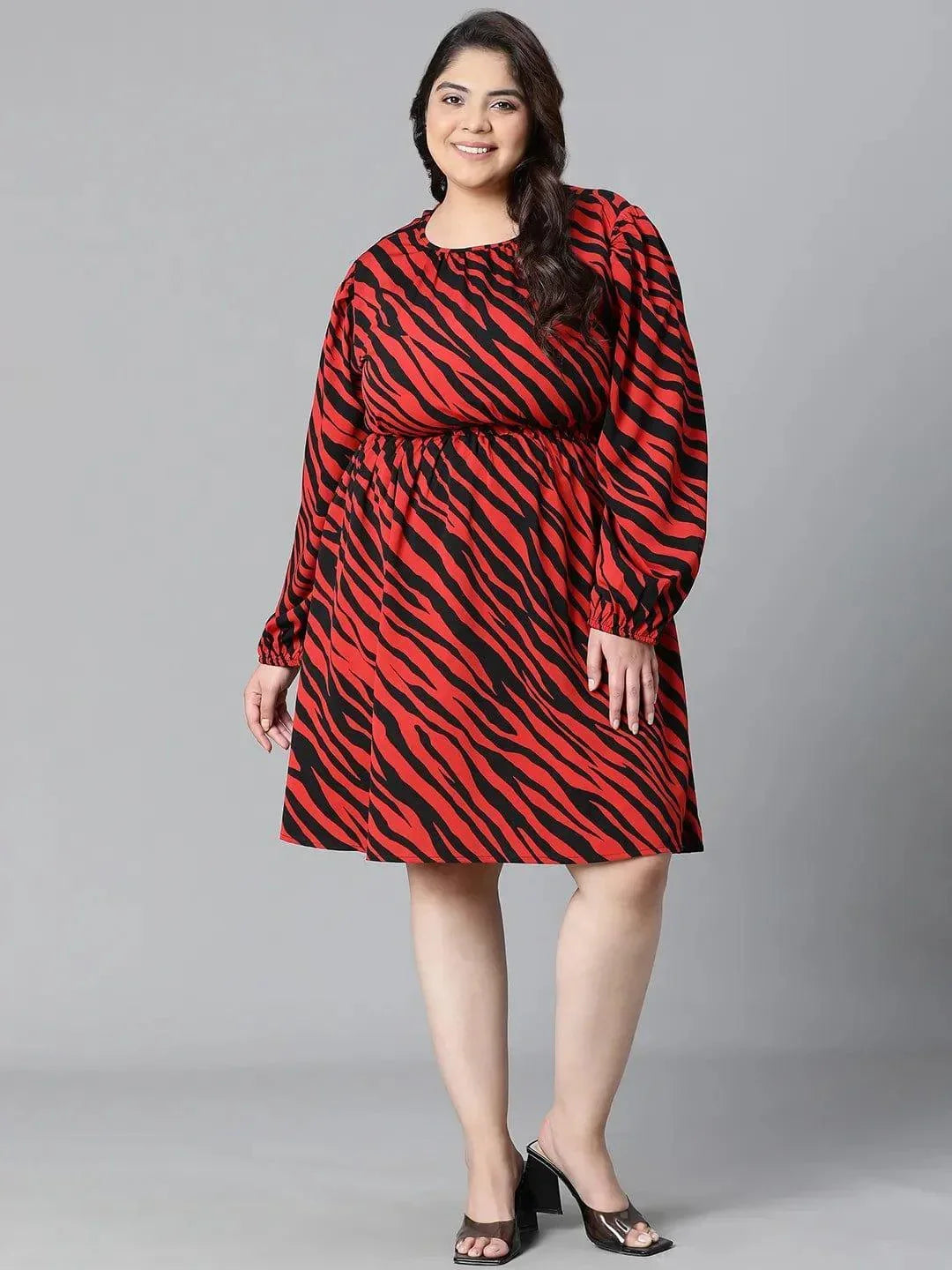 A woman wearing a red and black zebra print dress with long sleeves, smiling at the camera.