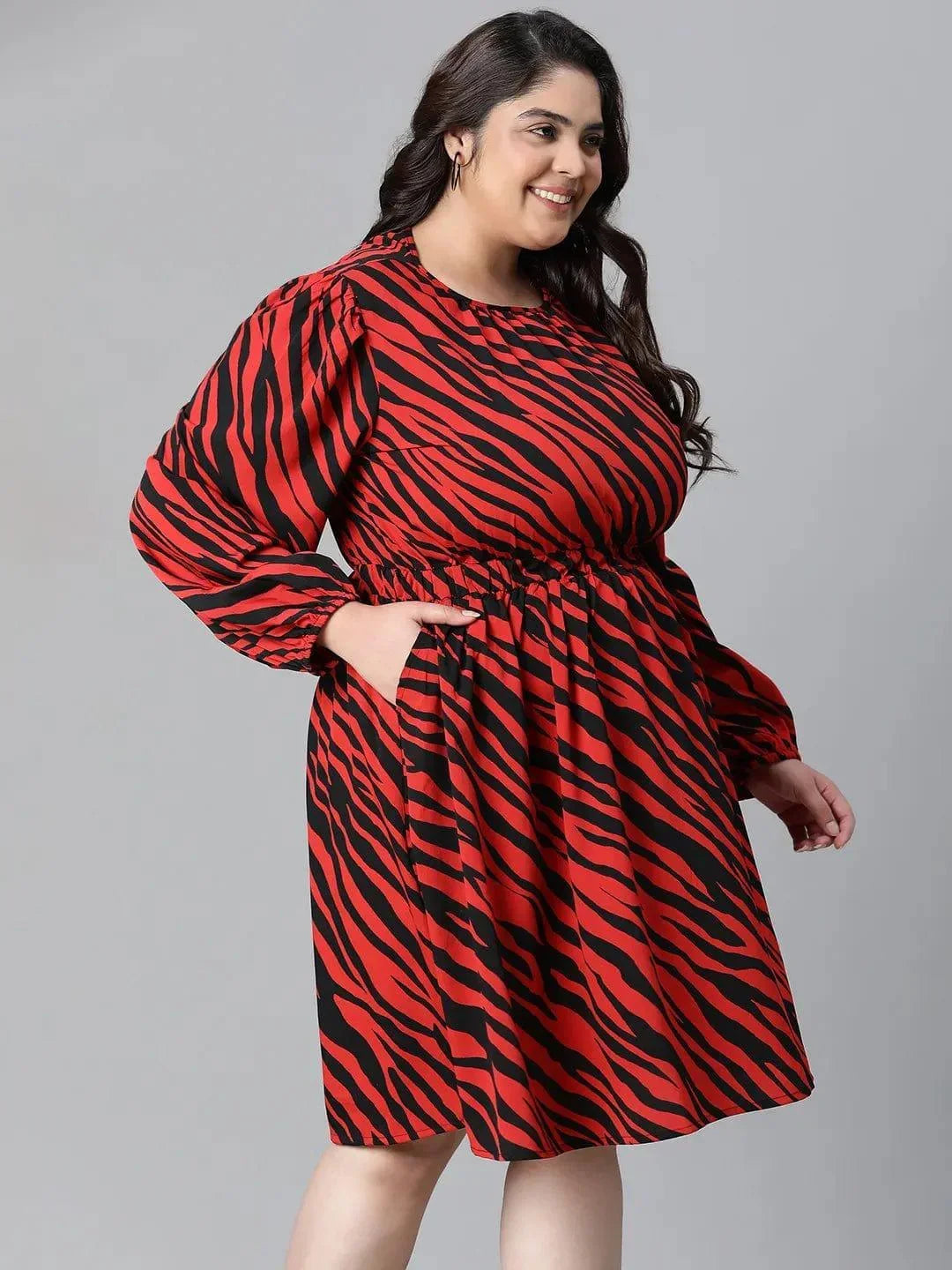 A woman wearing a red and black zebra print dress with long sleeves, smiling at the camera.