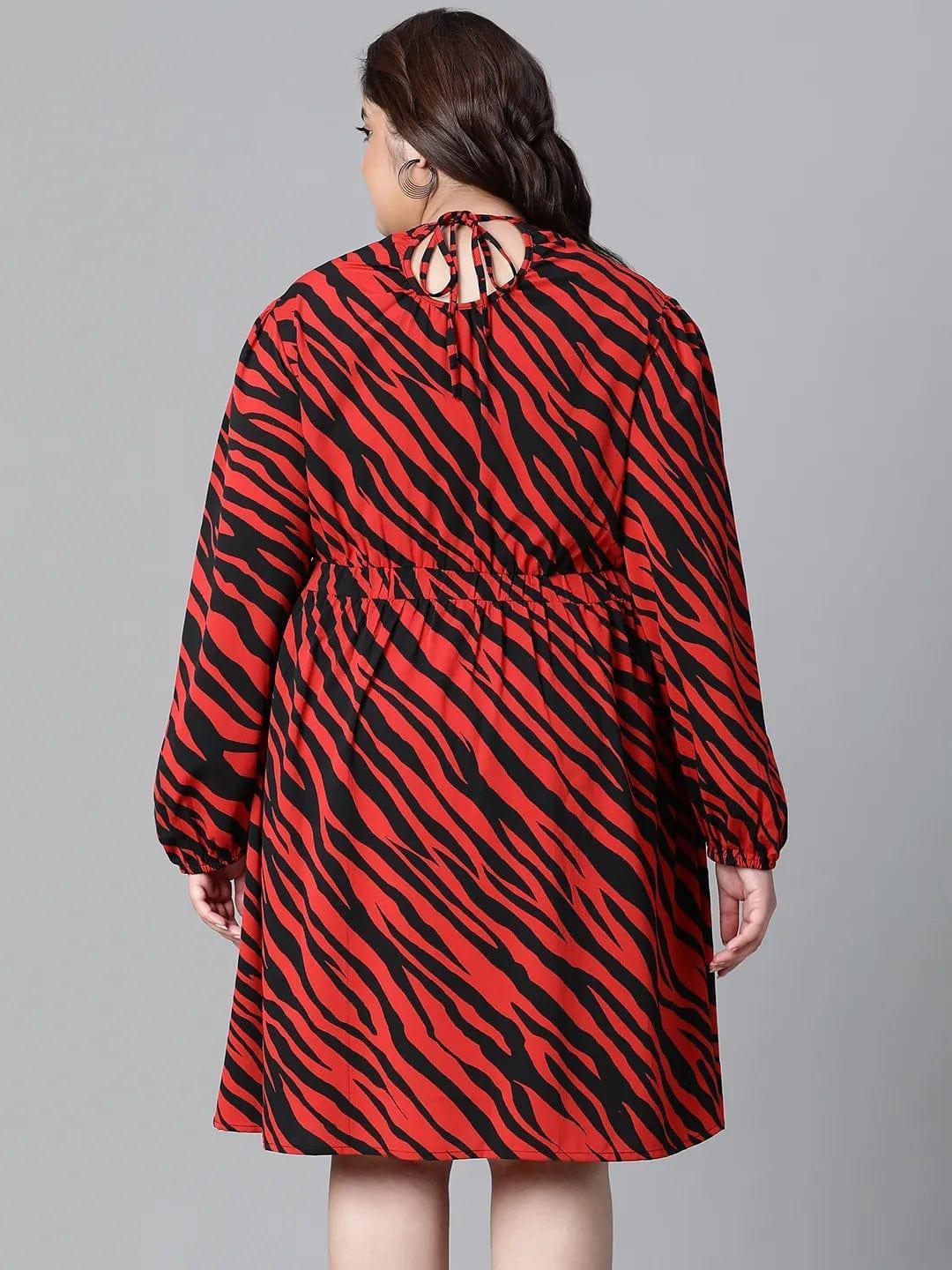 A woman wearing a red and black zebra print dress with long sleeves, smiling at the camera.
