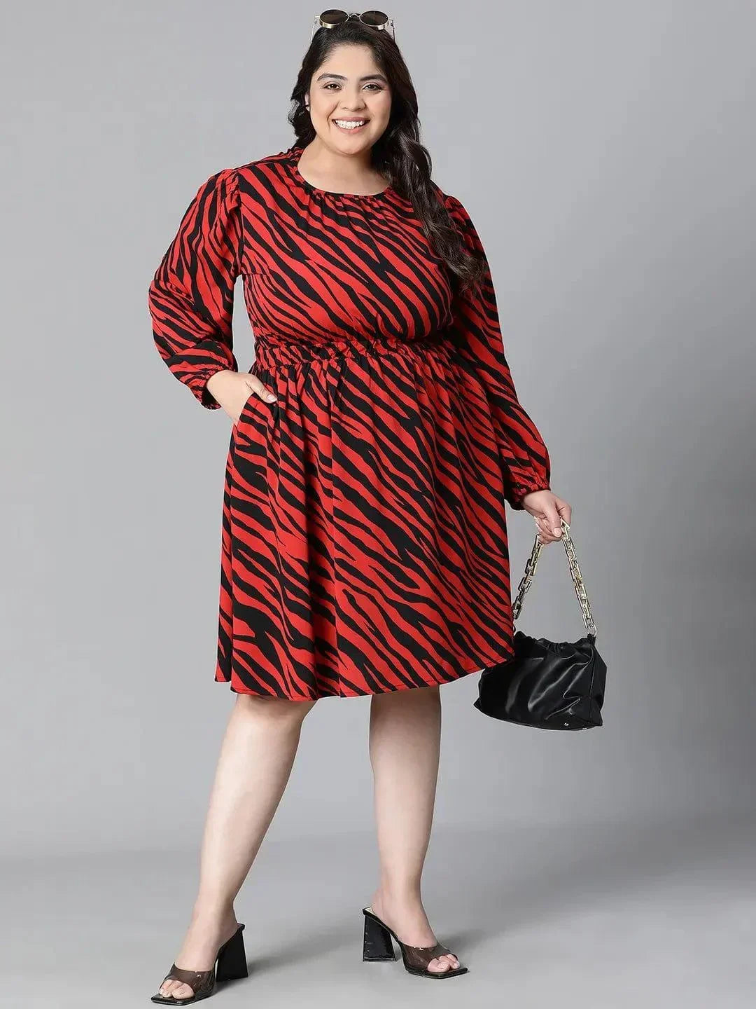 A woman wearing a red and black zebra print dress with long sleeves, smiling at the camera.