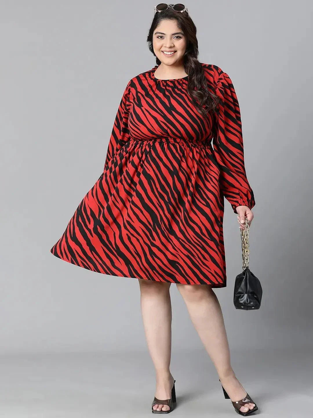 A woman wearing a red and black zebra print dress with long sleeves, smiling at the camera.