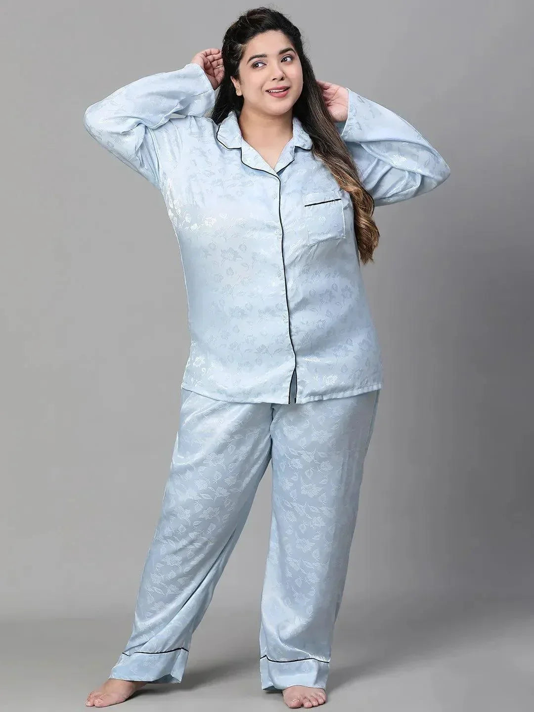 A woman wearing a light blue pajama top and matching pants, standing against a white background.