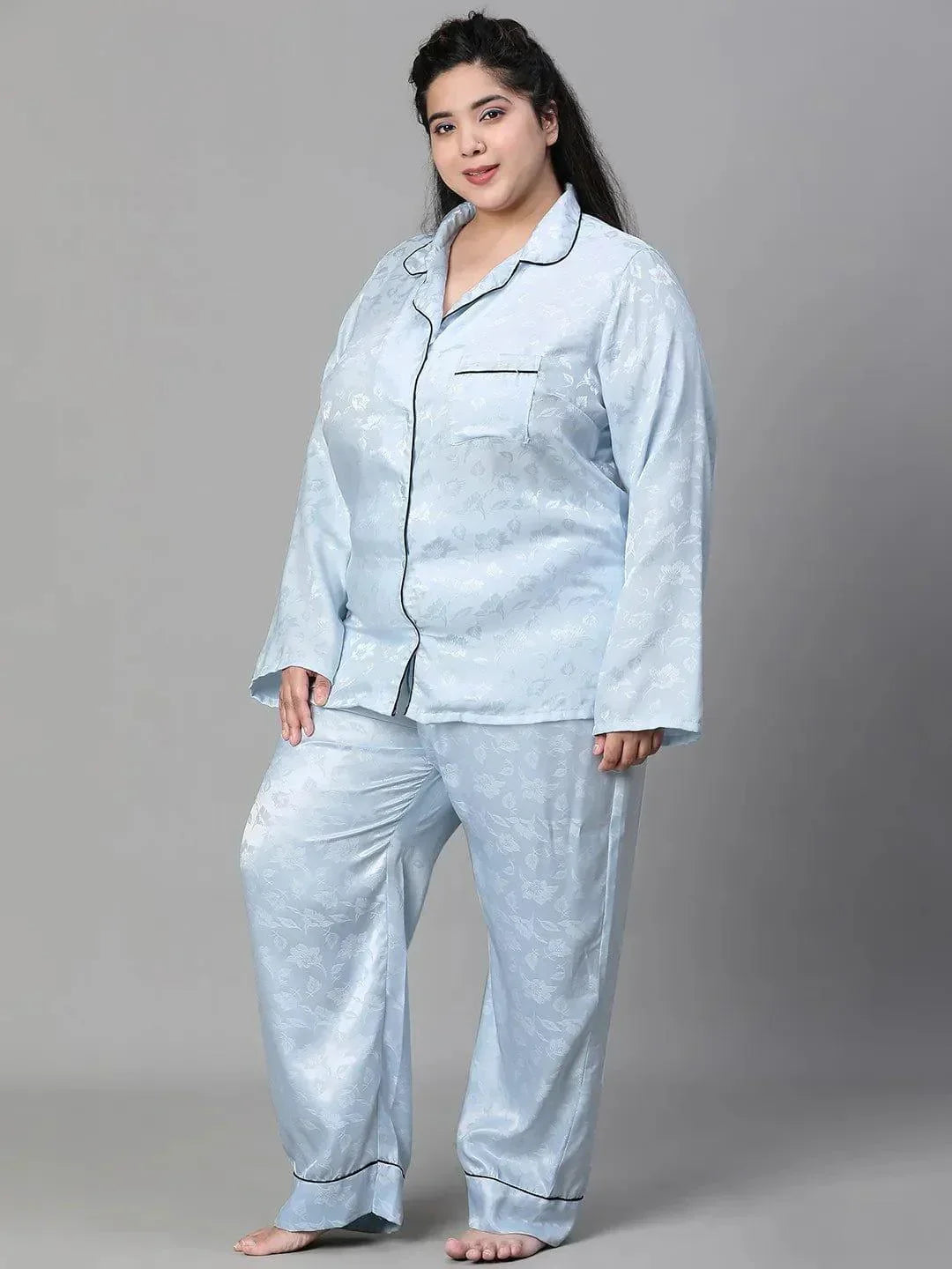 A woman wearing a light blue pajama top and matching pants, standing against a white background.