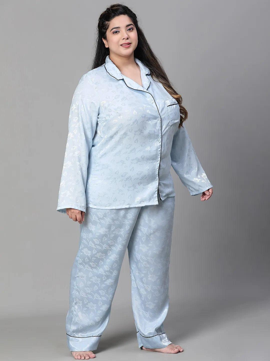 A woman wearing a light blue pajama top and matching pants, standing against a white background.