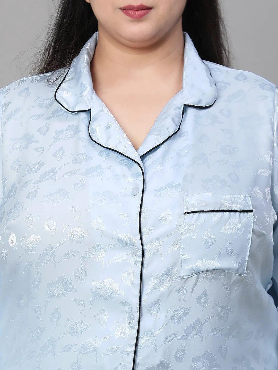 A woman wearing a light blue pajama top and matching pants, standing against a white background.
