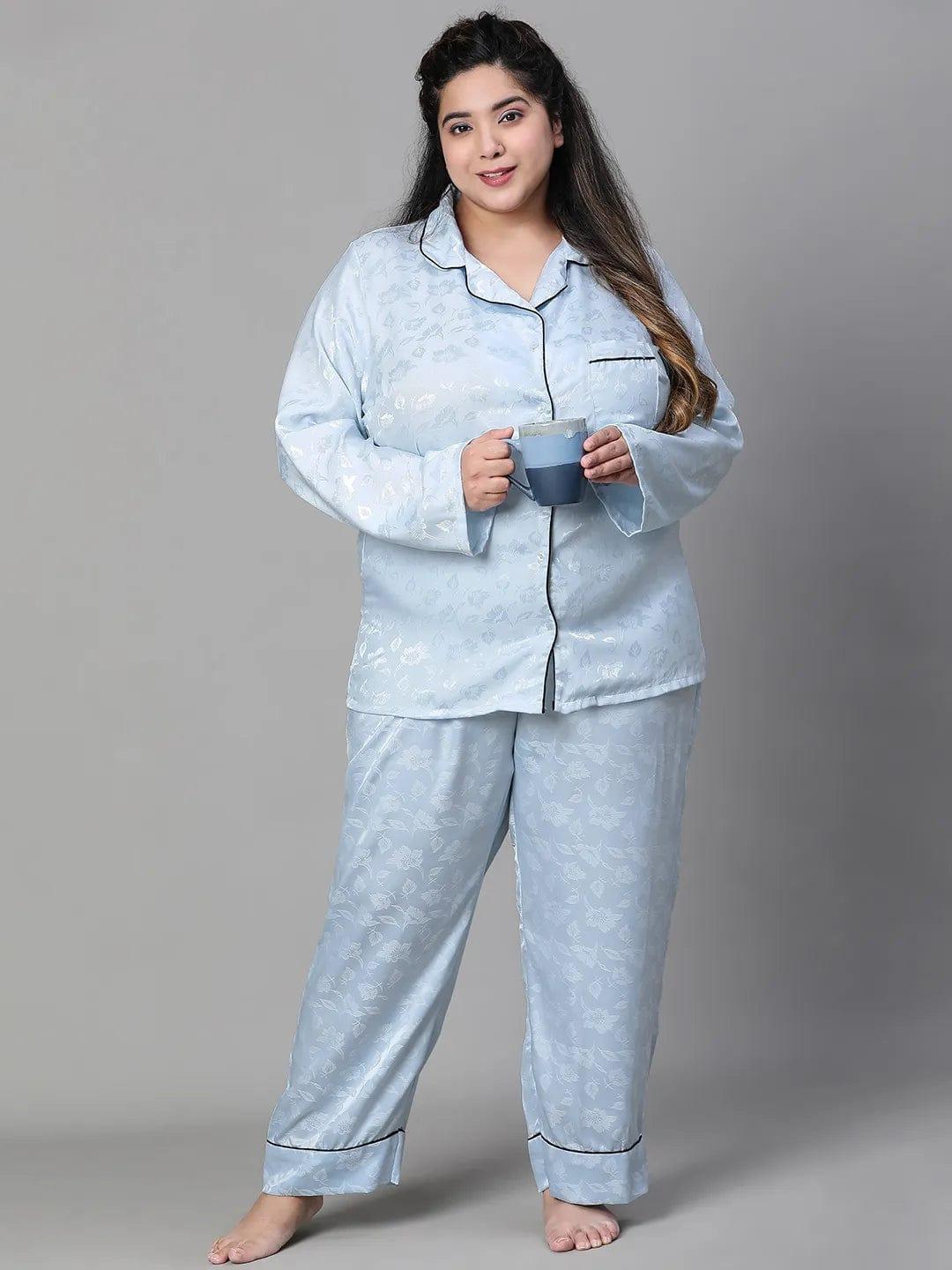 A woman wearing a light blue pajama top and matching pants, standing against a white background.