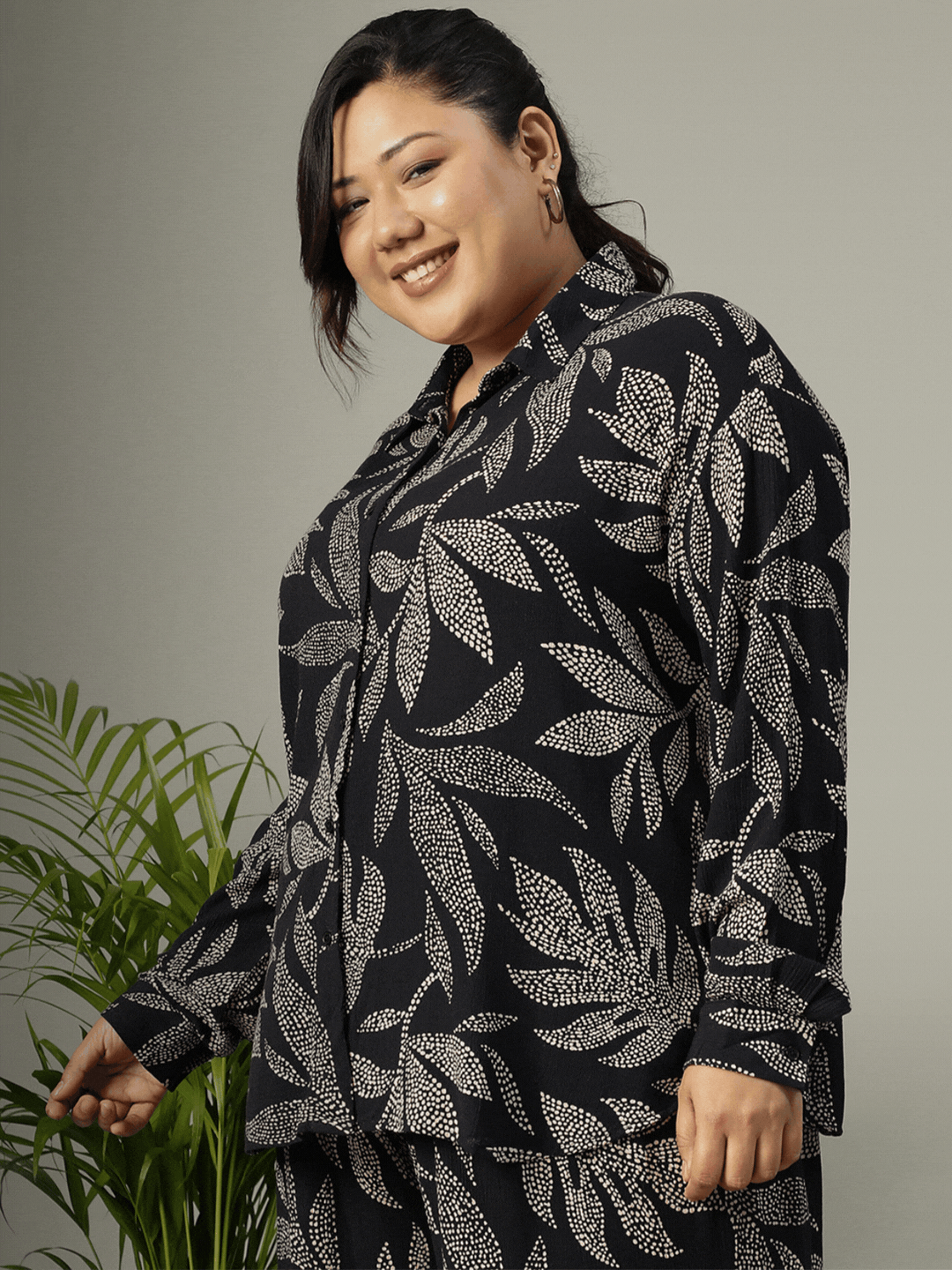 A woman wearing a black and white patterned shirt and skirt is smiling at the camera.