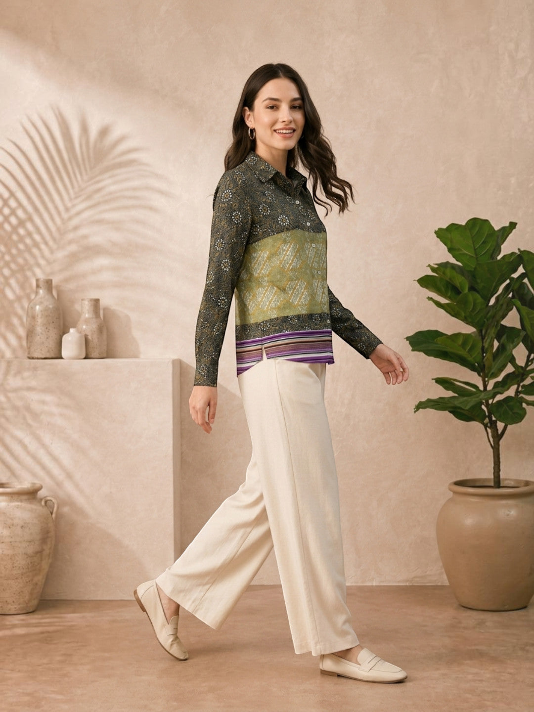 Woman in patterned long sleeve blouse and cream wide-leg pants, stylish plus size fashion outfit