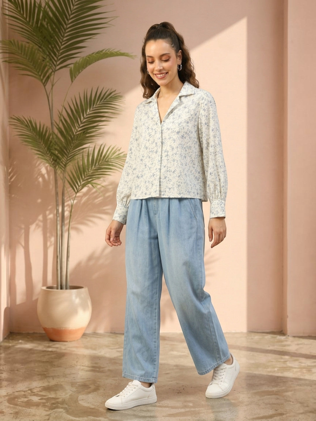 Woman in floral blouse and light blue wide-leg jeans, styled with white sneakers for casual fashion