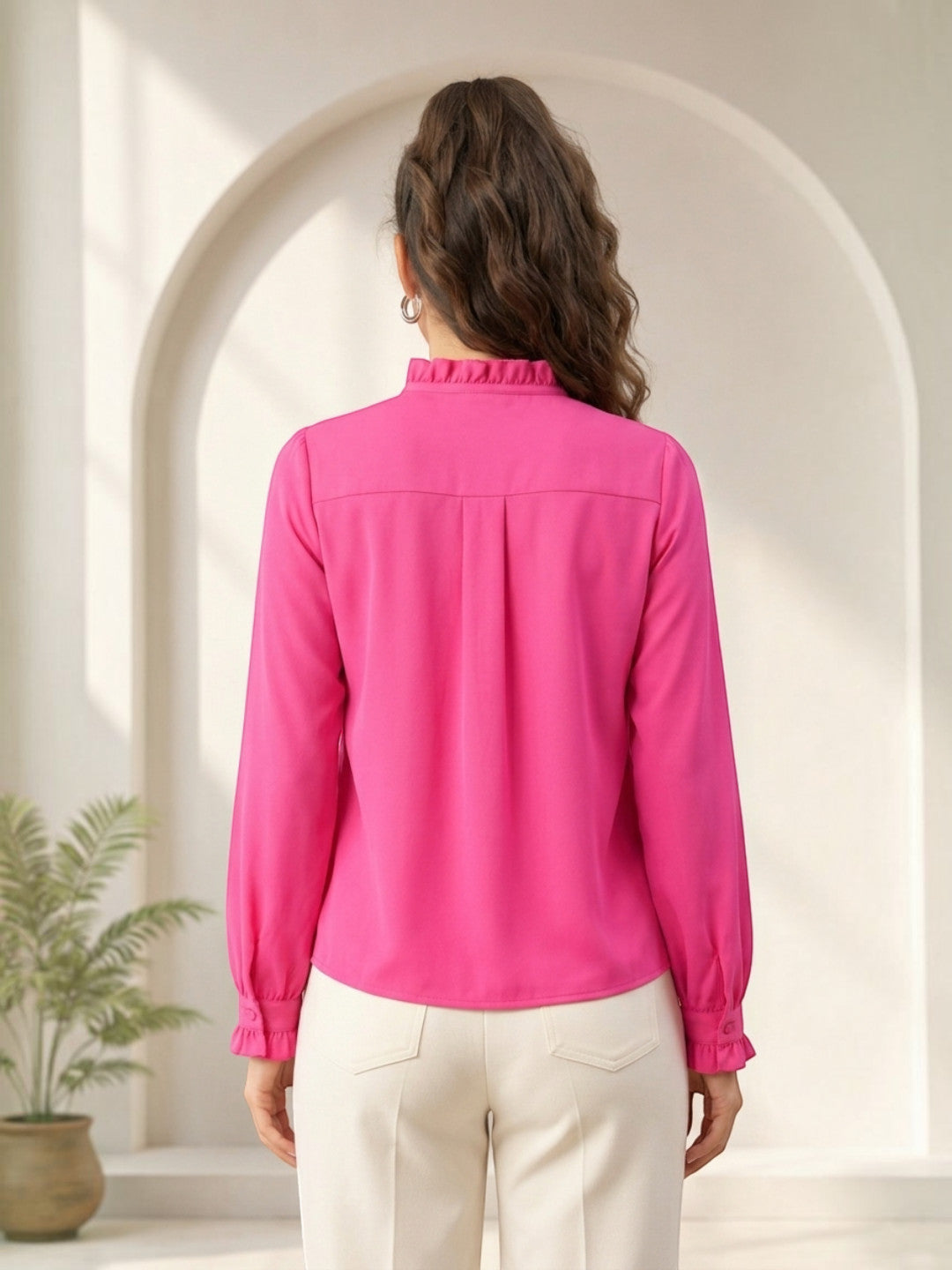 Pink long sleeve blouse with ruffled collar and cuffs, paired with white pants, back view