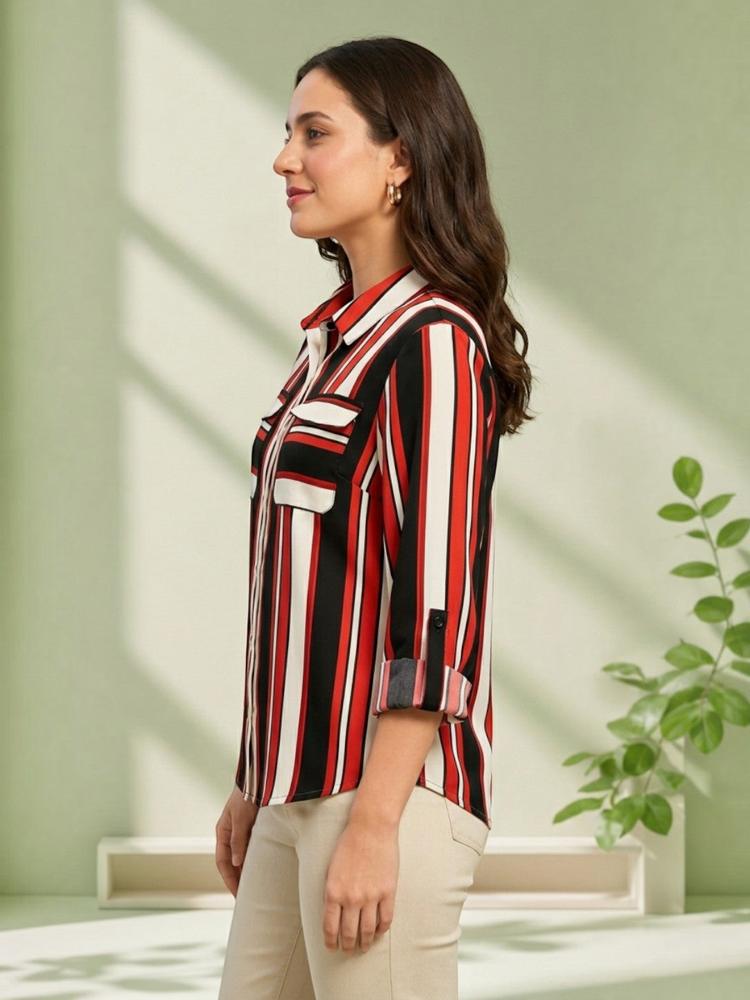 Woman in red black white striped button-up shirt with rolled sleeves, beige pants, side profile