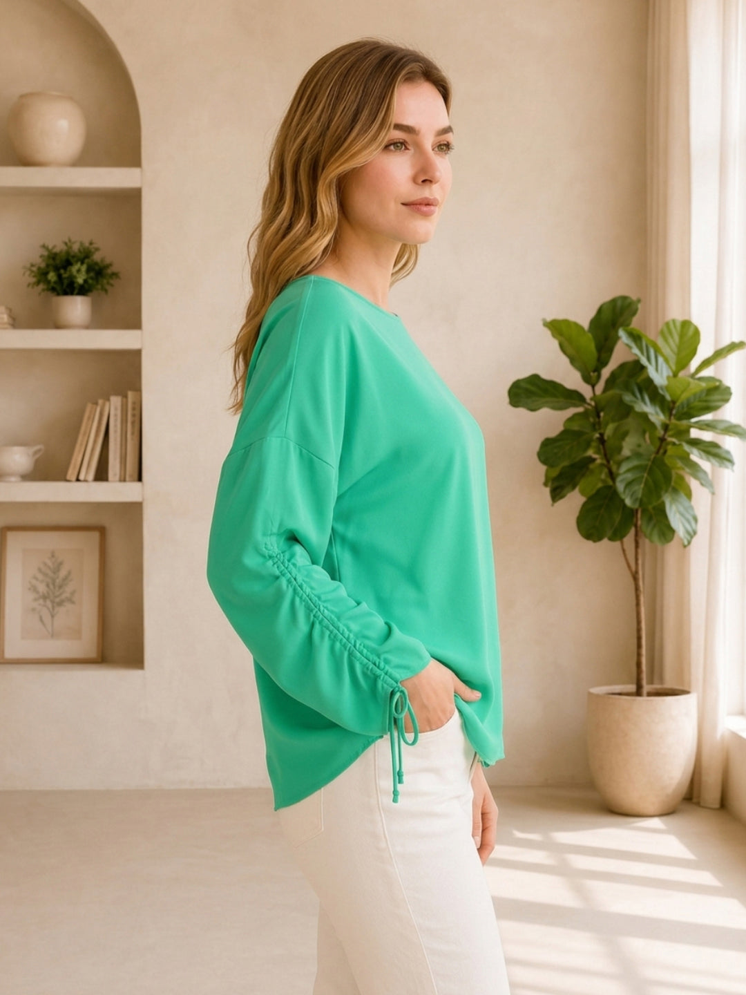 Green long-sleeve drawstring top paired with white pants, stylish women's fashion