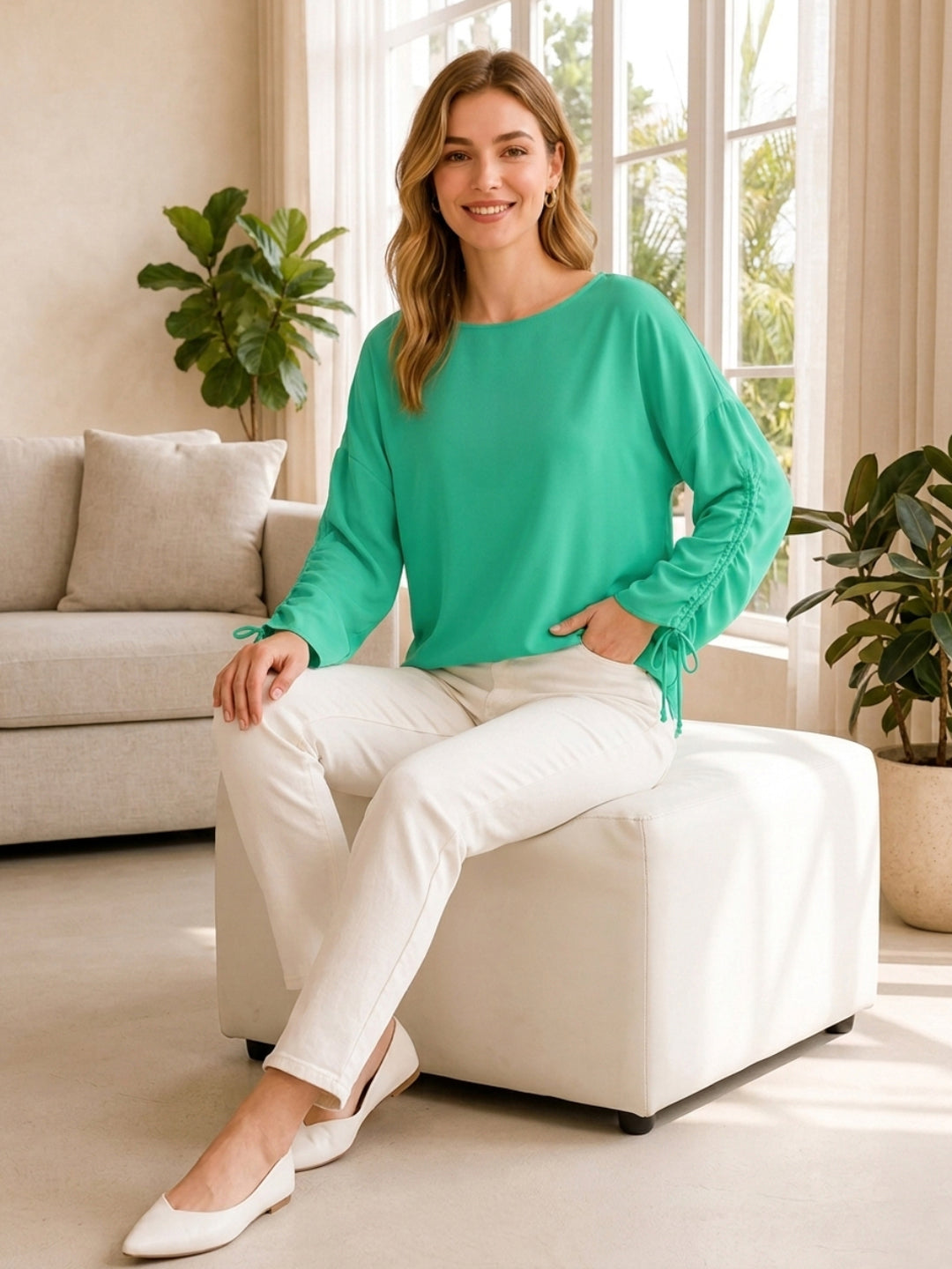 Woman in green long-sleeve top and white pants, stylish plus size fashion outfit