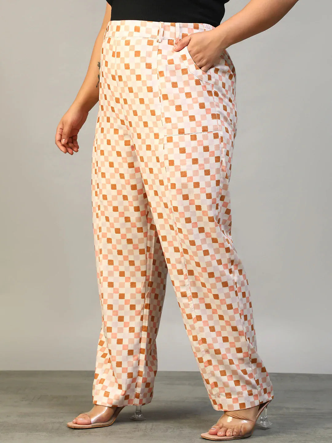A person wearing a pair of wide-leg pants with a checkered pattern in shades of pink and white.