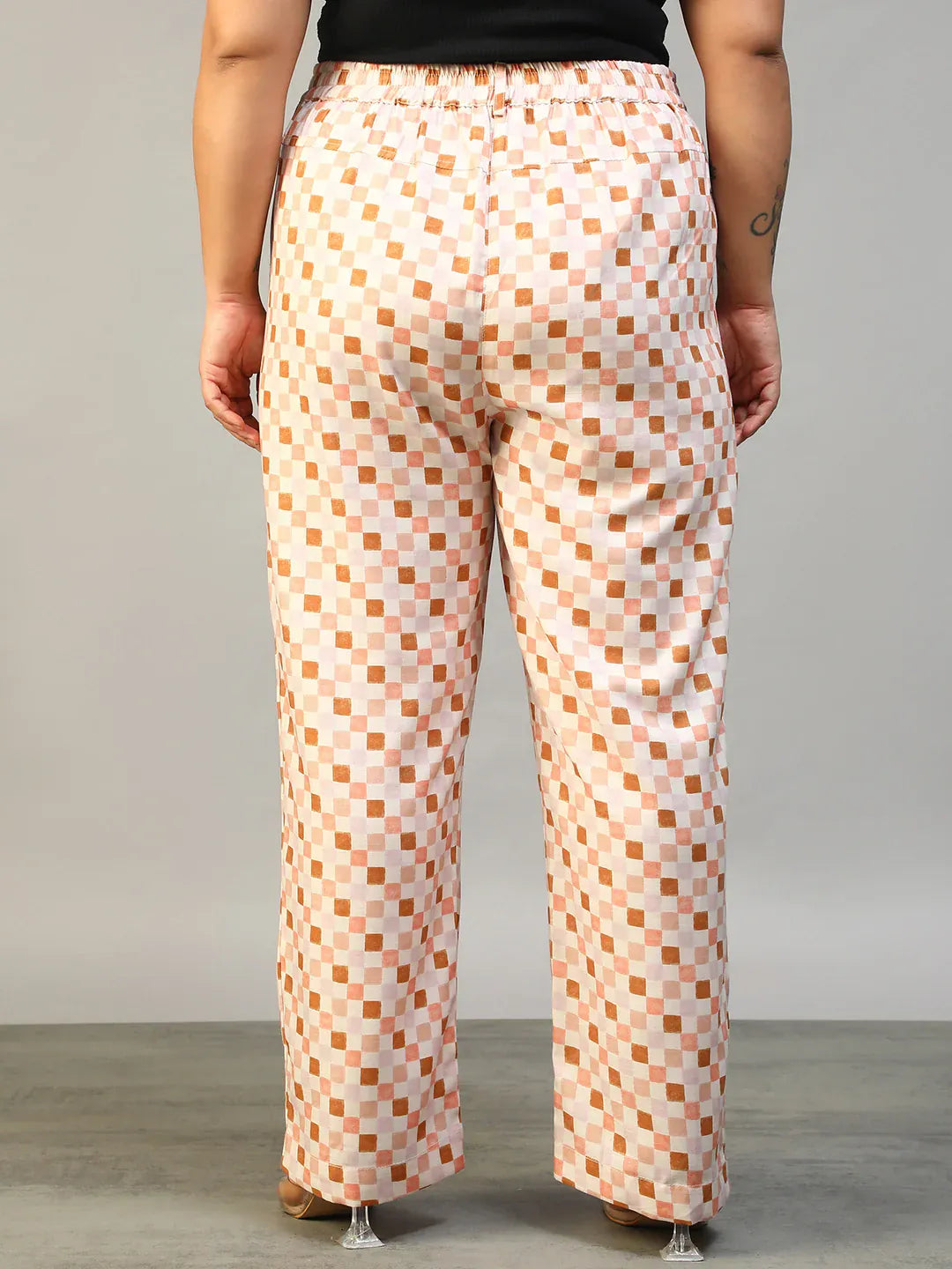 A person wearing a pair of wide-leg pants with a checkered pattern in shades of pink and white.