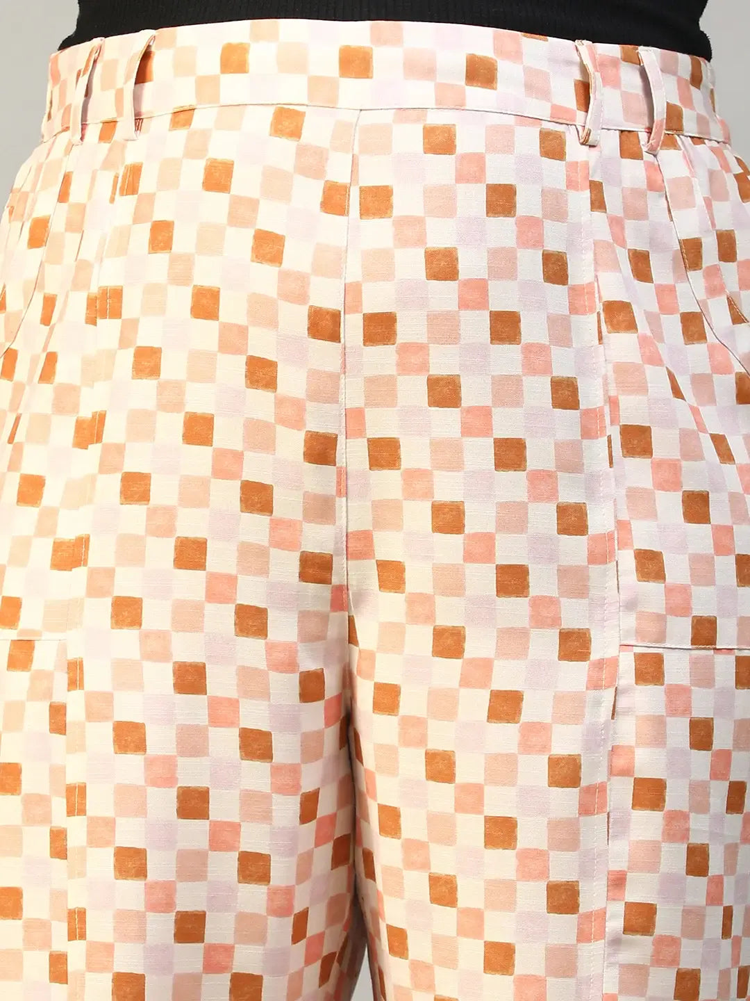 A person wearing a pair of wide-leg pants with a checkered pattern in shades of pink and white.