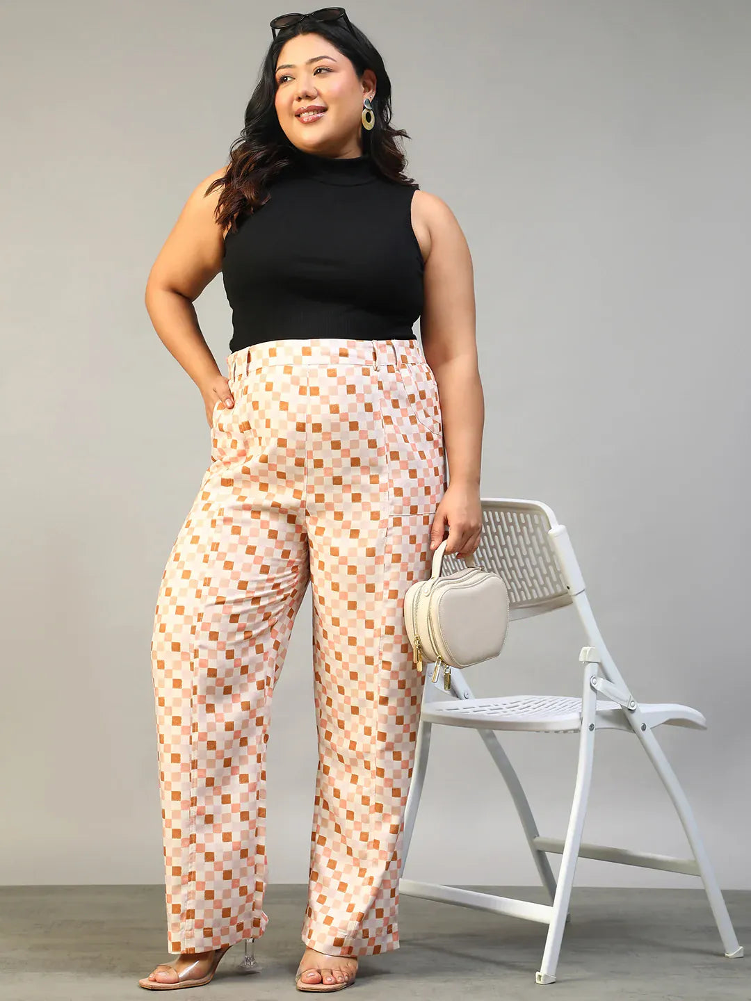 A person wearing a pair of wide-leg pants with a checkered pattern in shades of pink and white.