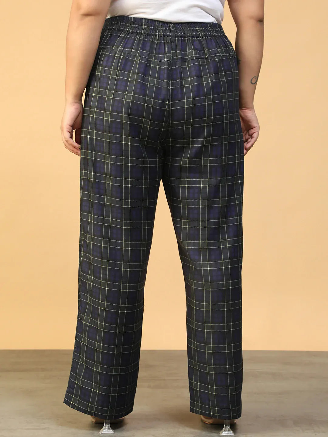 A person wearing a pair of black and green plaid pants.