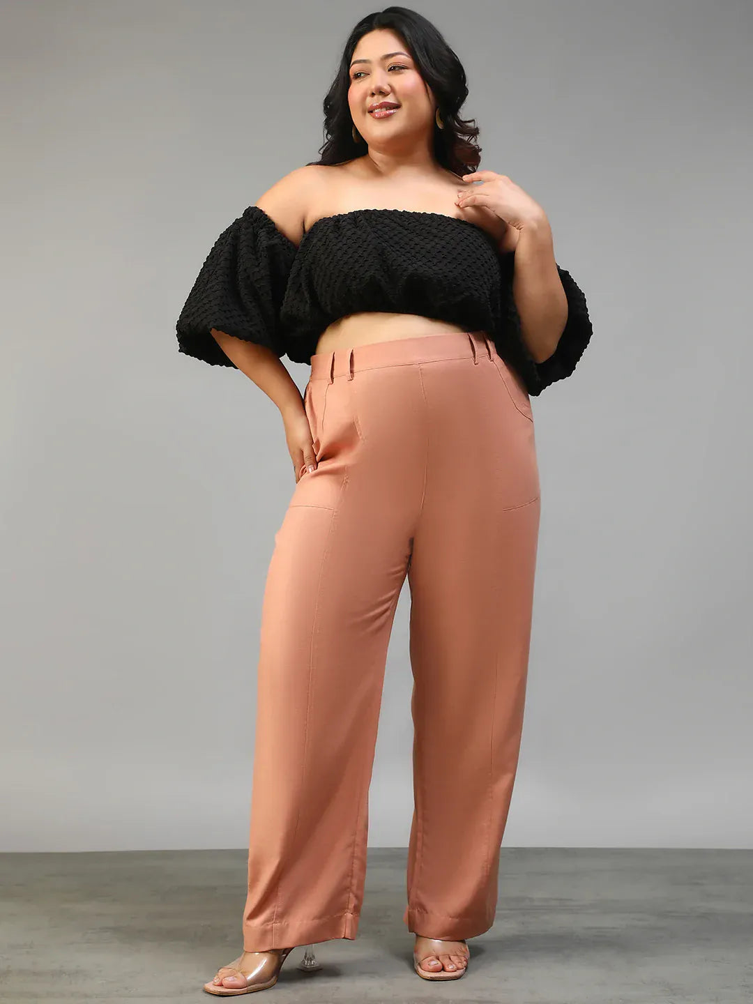 A woman wearing peach-colored wide-leg pants with a high waist and a black top.