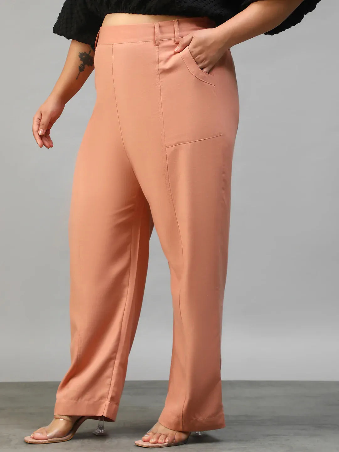 A woman wearing peach-colored wide-leg pants with a high waist and a black top.