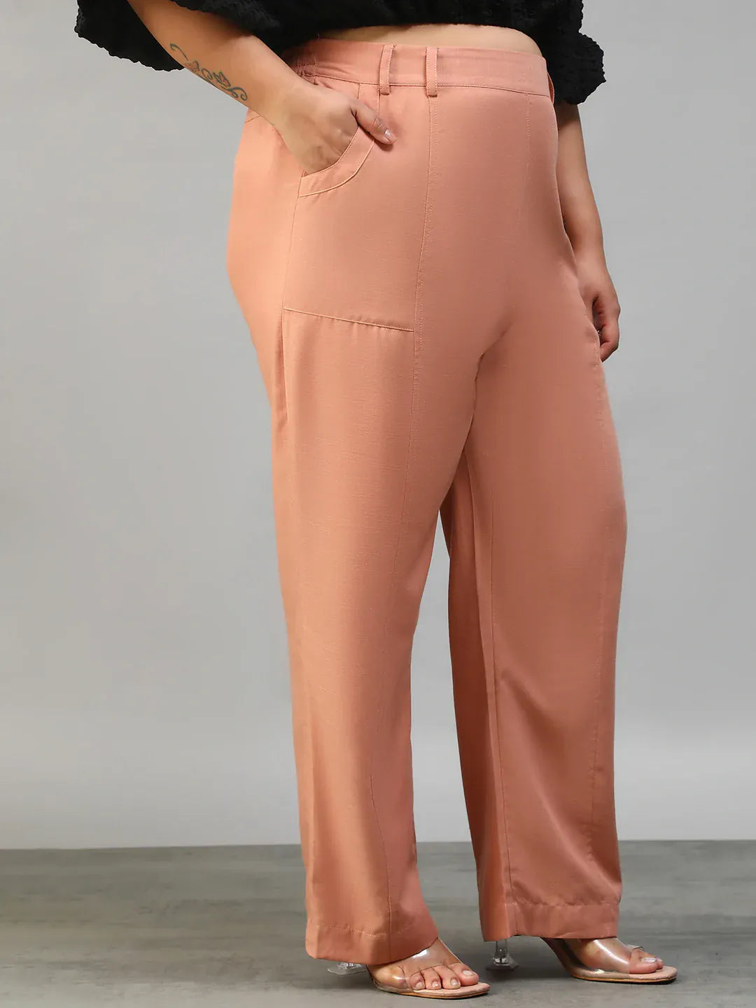 A woman wearing peach-colored wide-leg pants with a high waist and a black top.