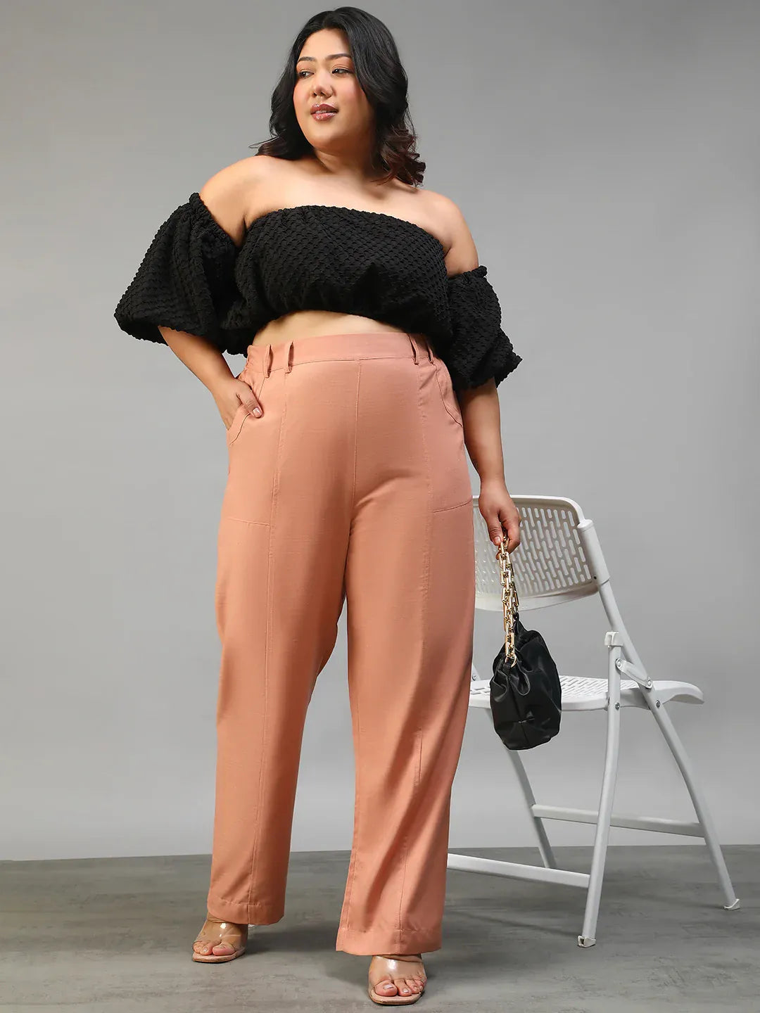 A woman wearing peach-colored wide-leg pants with a high waist and a black top.