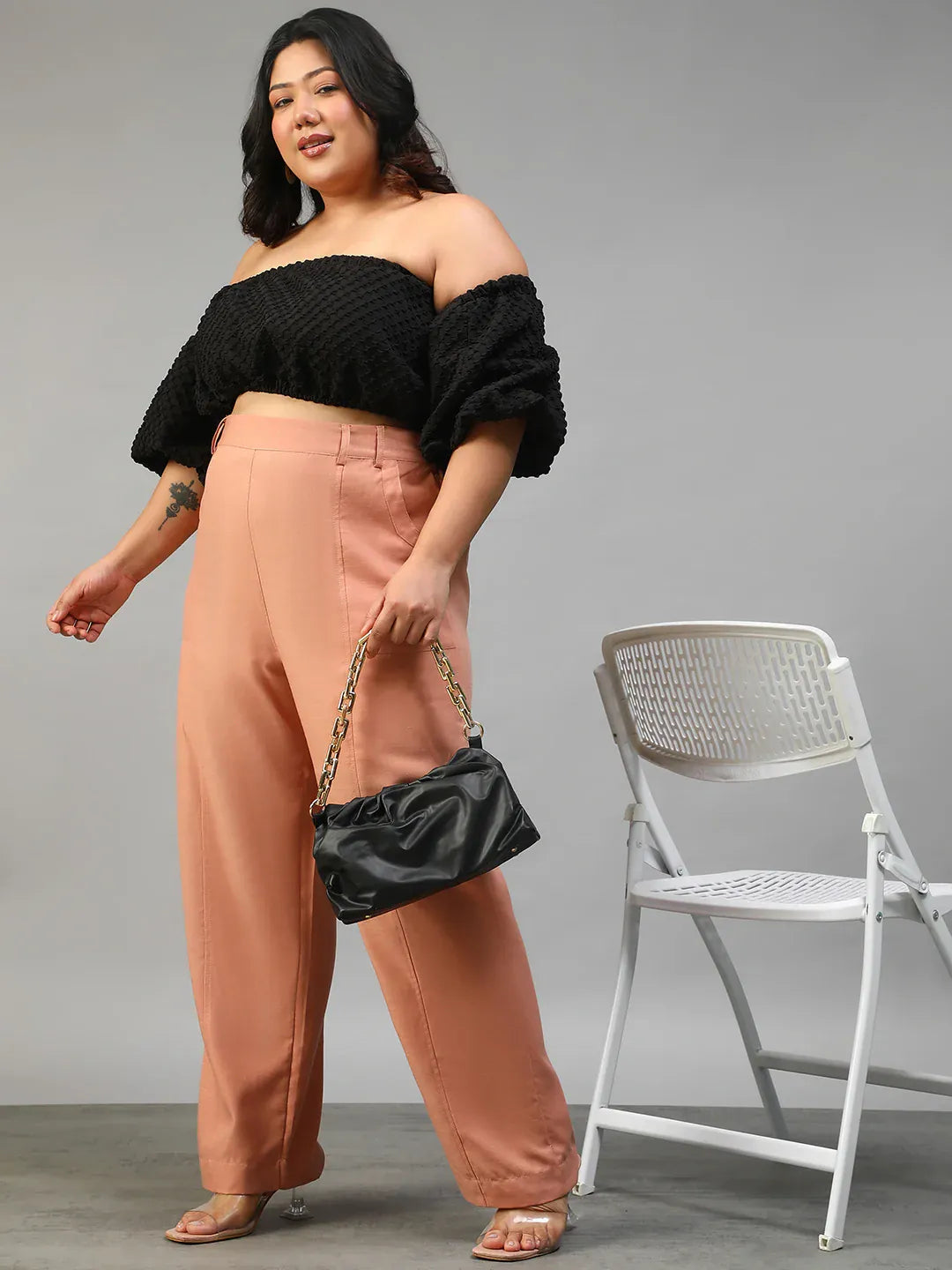 A woman wearing peach-colored wide-leg pants with a high waist and a black top.