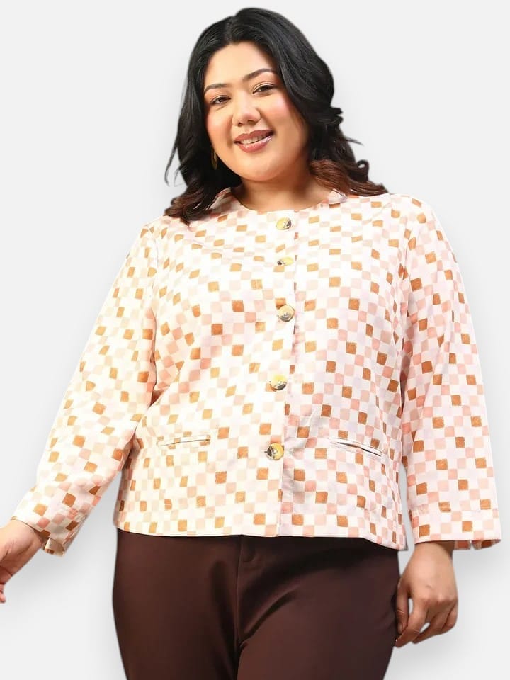 A smiling woman with long dark hair wearing a white and orange checkered jacket with buttons.