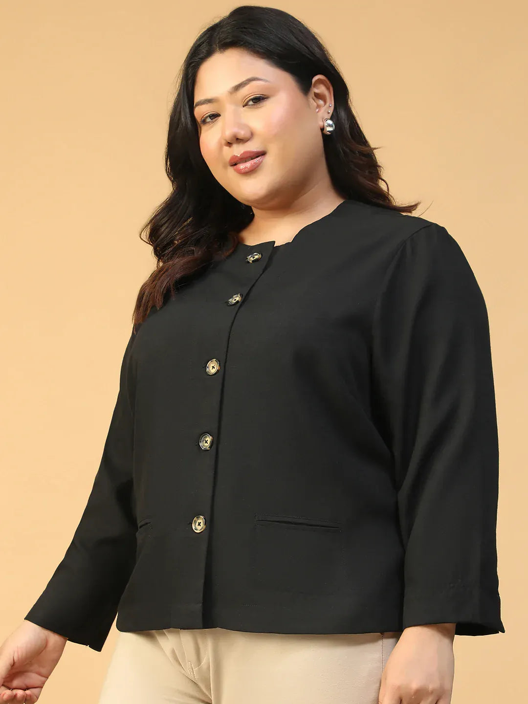 A woman with long dark hair wearing a black jacket with gold buttons, smiling at the camera.