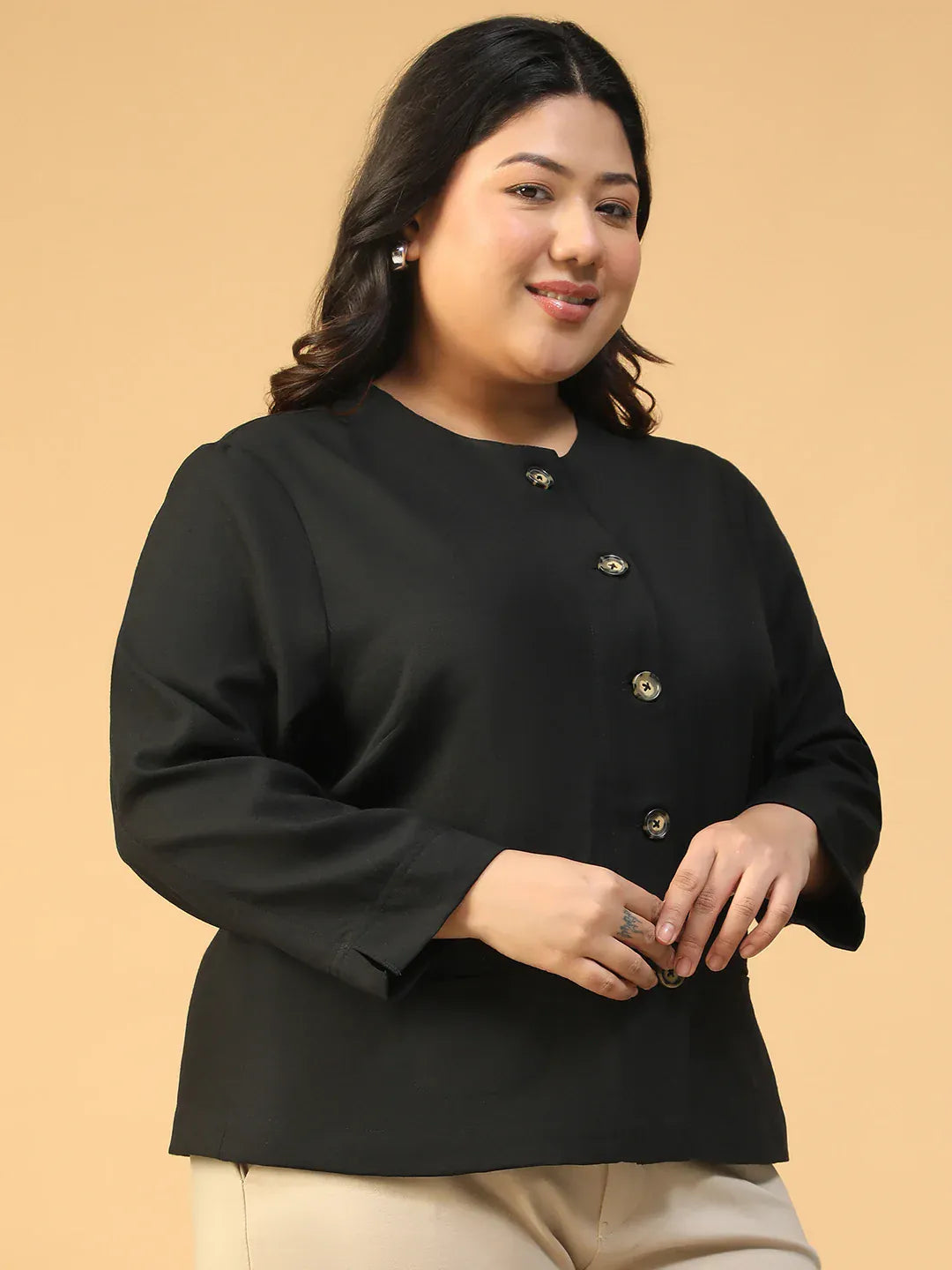 A woman with long dark hair wearing a black jacket with gold buttons, smiling at the camera.