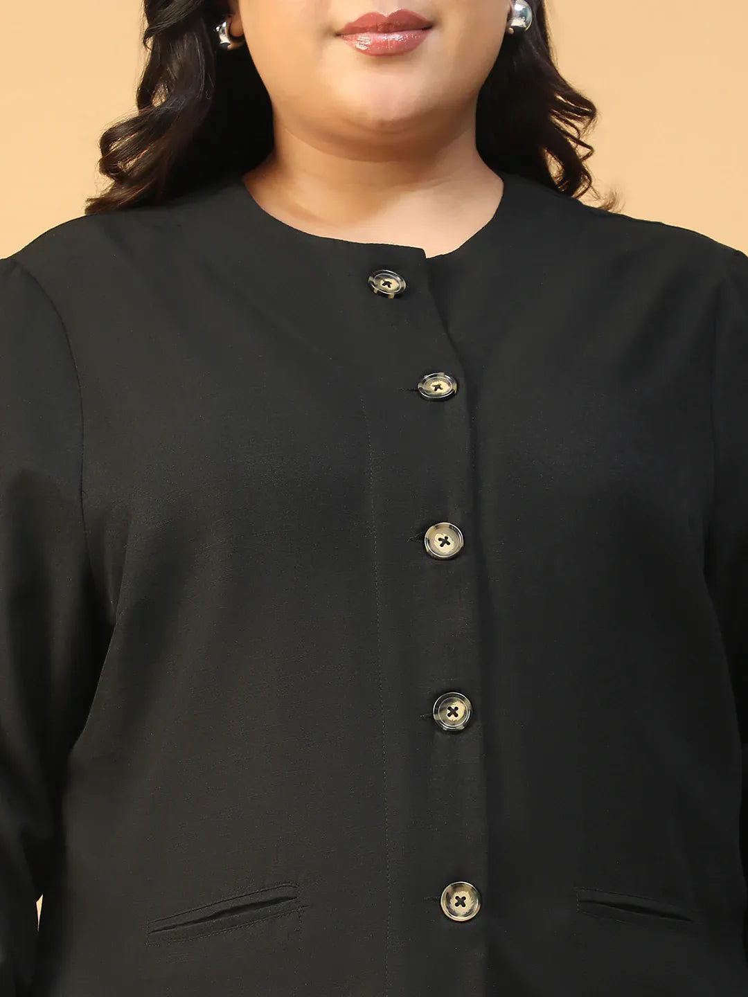 A woman with long dark hair wearing a black jacket with gold buttons, smiling at the camera.