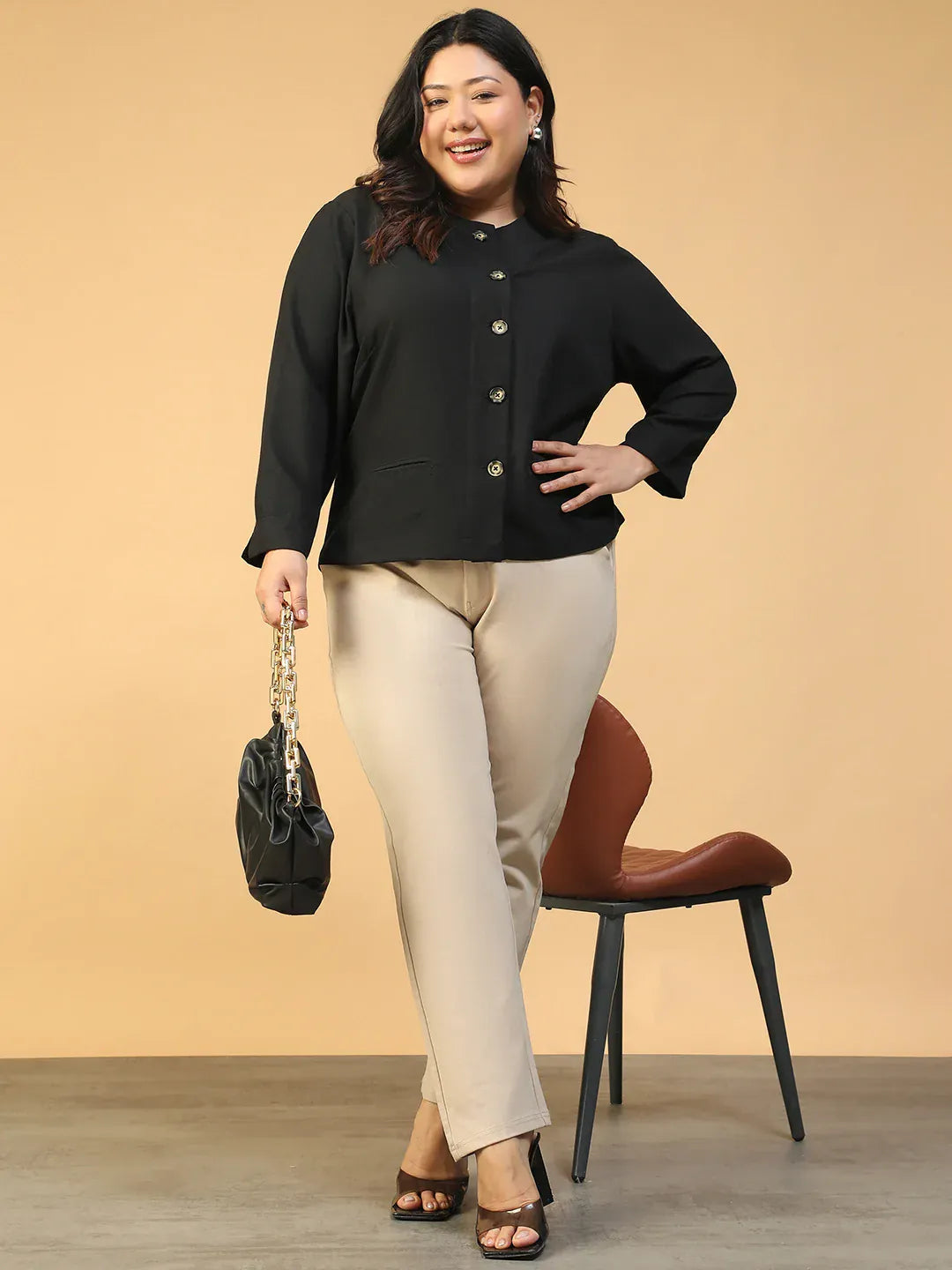 A woman with long dark hair wearing a black jacket with gold buttons, smiling at the camera.