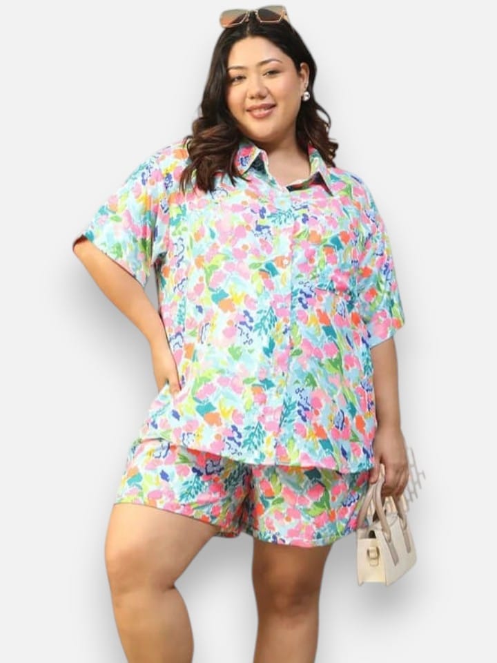 A woman wearing a colorful floral print shirt is smiling and posing for the camera.