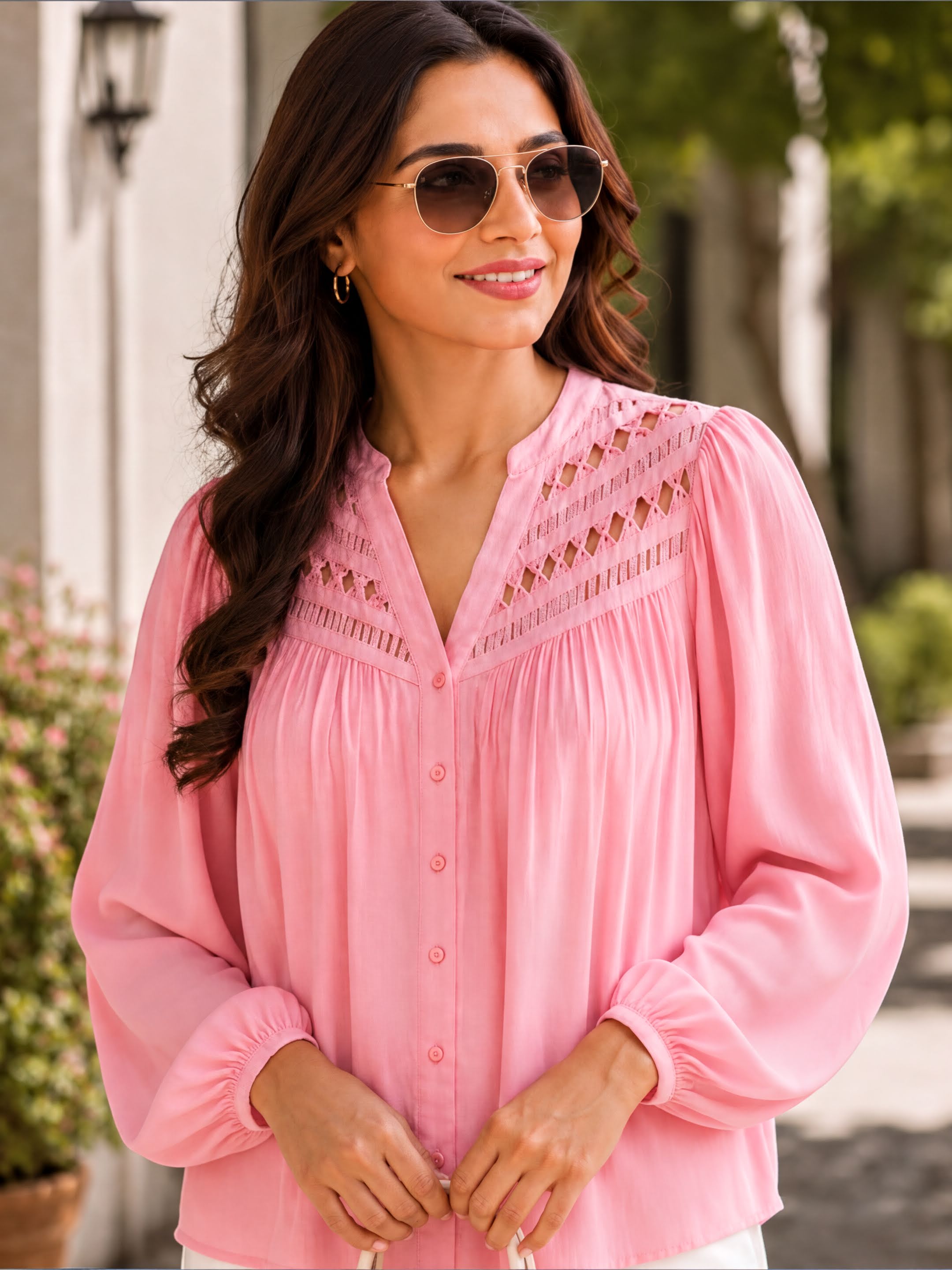 A woman wearing a pink blouse with a ruched collar and puffed sleeves, smiling and looking to the side.
