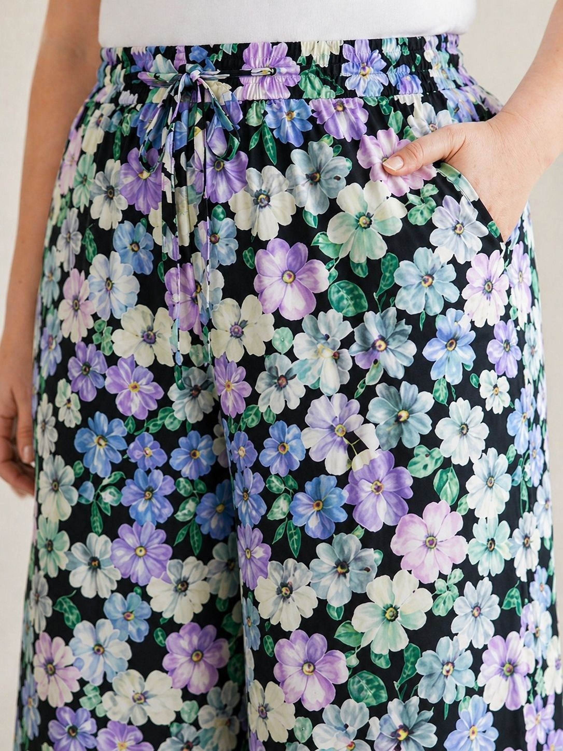 A pair of wide-leg pants with a floral print in shades of purple, blue, and white.